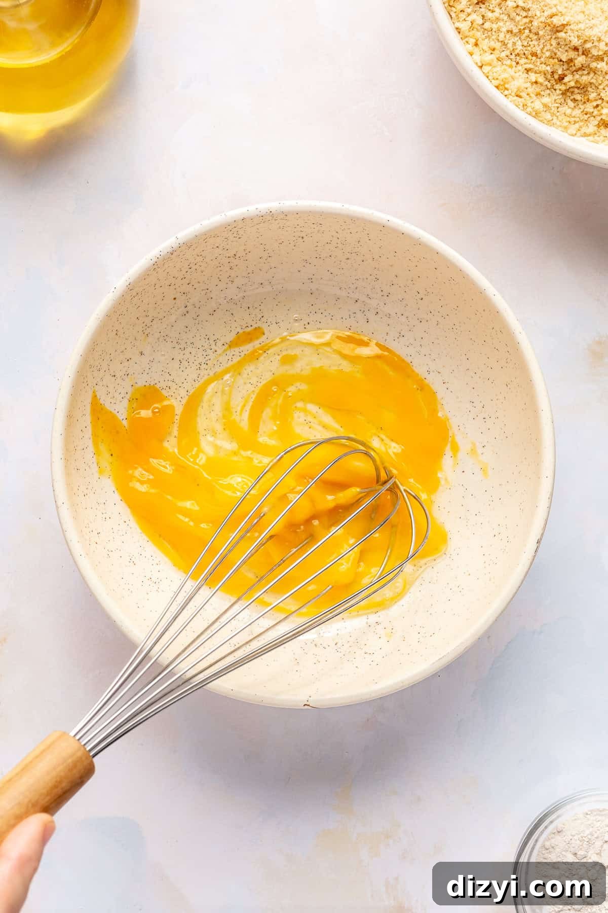 Egg wash getting whisked in small bowl.