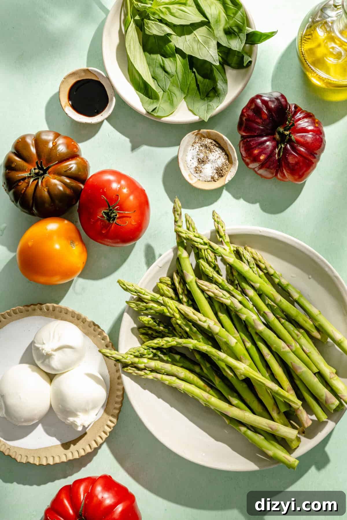 Burrata Caprese Salad with Asparagus and Tomatoes 3 a flat lay of ingredients for caprese salad with fresh asparagus, tomatoes, basil, garlic, and olive oil