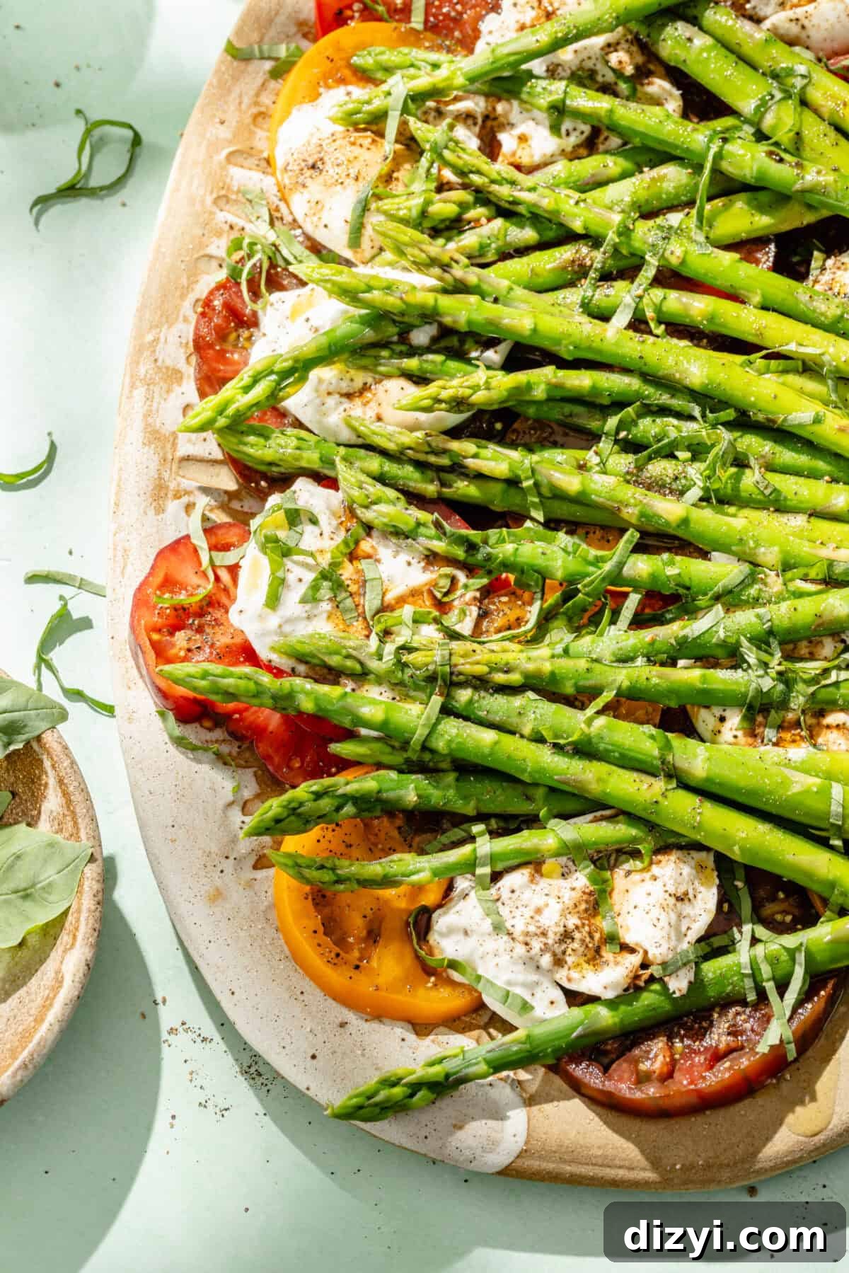 Burrata Caprese Salad with Asparagus and Tomatoes 5 caprese salad with blanched asparagus on a light blue background
