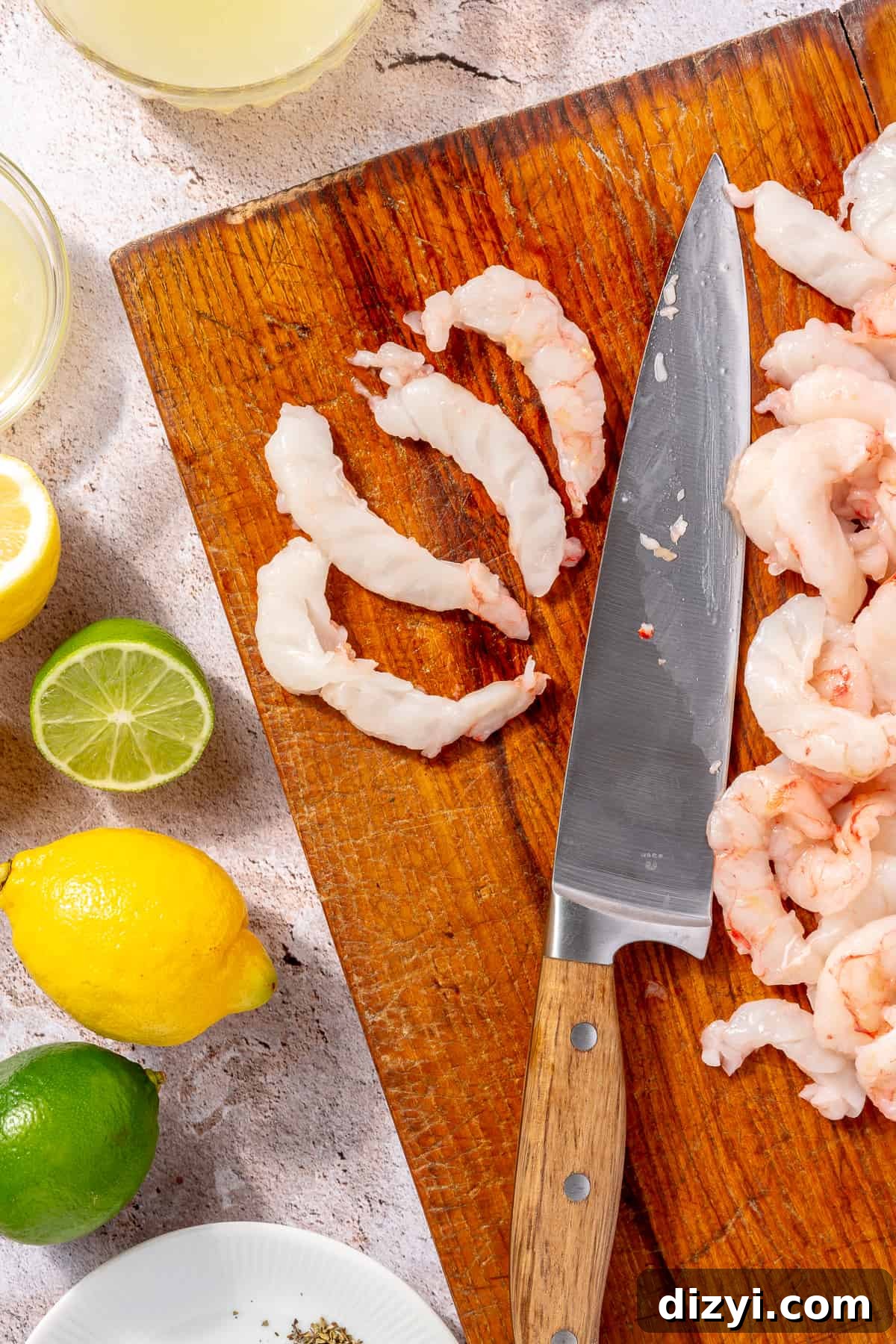 Raw shrimp on cutting board. Two pieces of shrimp sliced lengthwise.