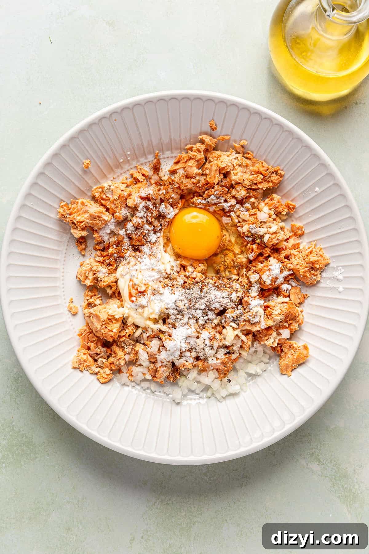 A white bowl with the salmon croquette ingredients, ready to be combined.