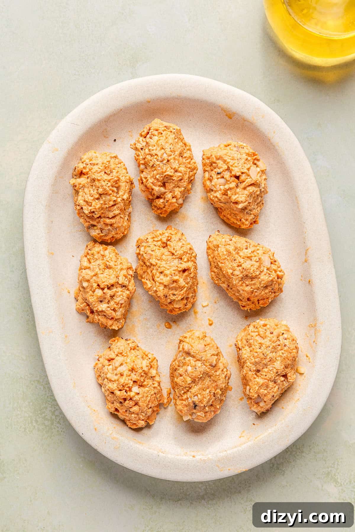 An oval platter with nine formed croquettes, not yet cooked.