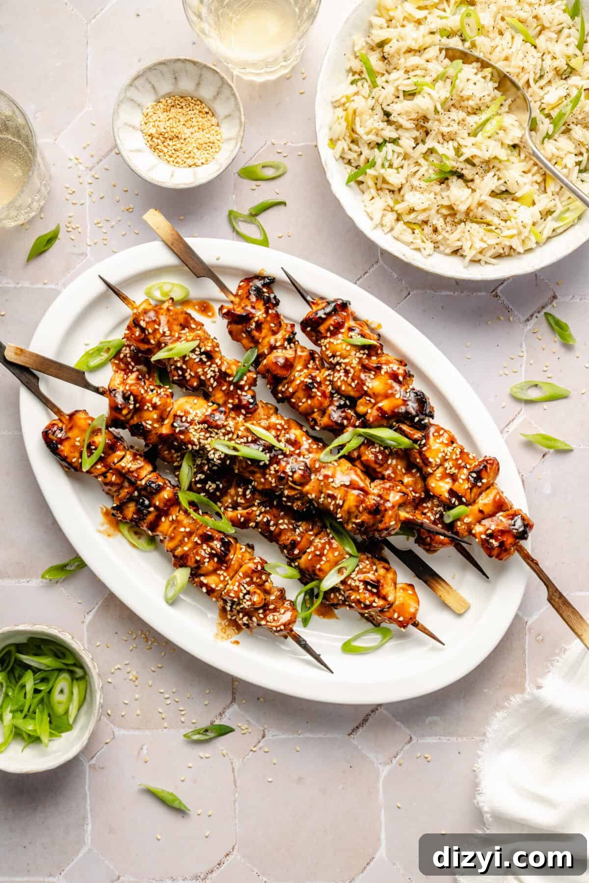 a plate of sesame chicken skewers garnished with scallions and served with rice