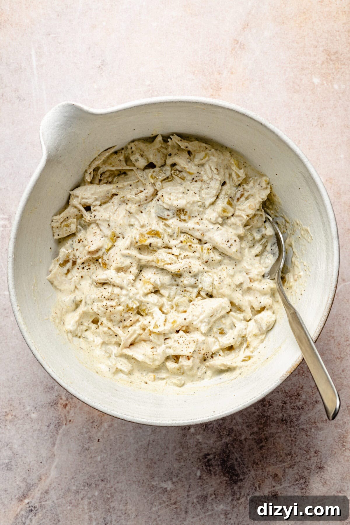 Creamy Green Chile Chicken Enchiladas 4 a white mixing bowl with shredded chicken tossed with sour cream