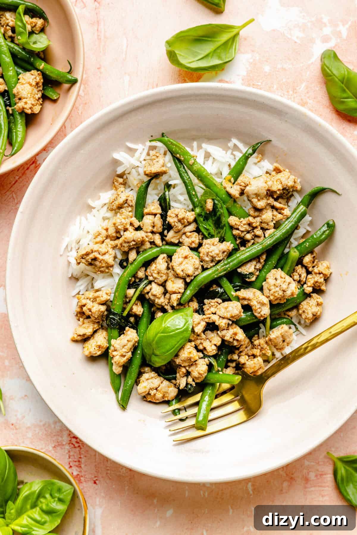 A white dish with the turkey, green bean, and basil dish inside, with a gold fork in the bowl as well.
