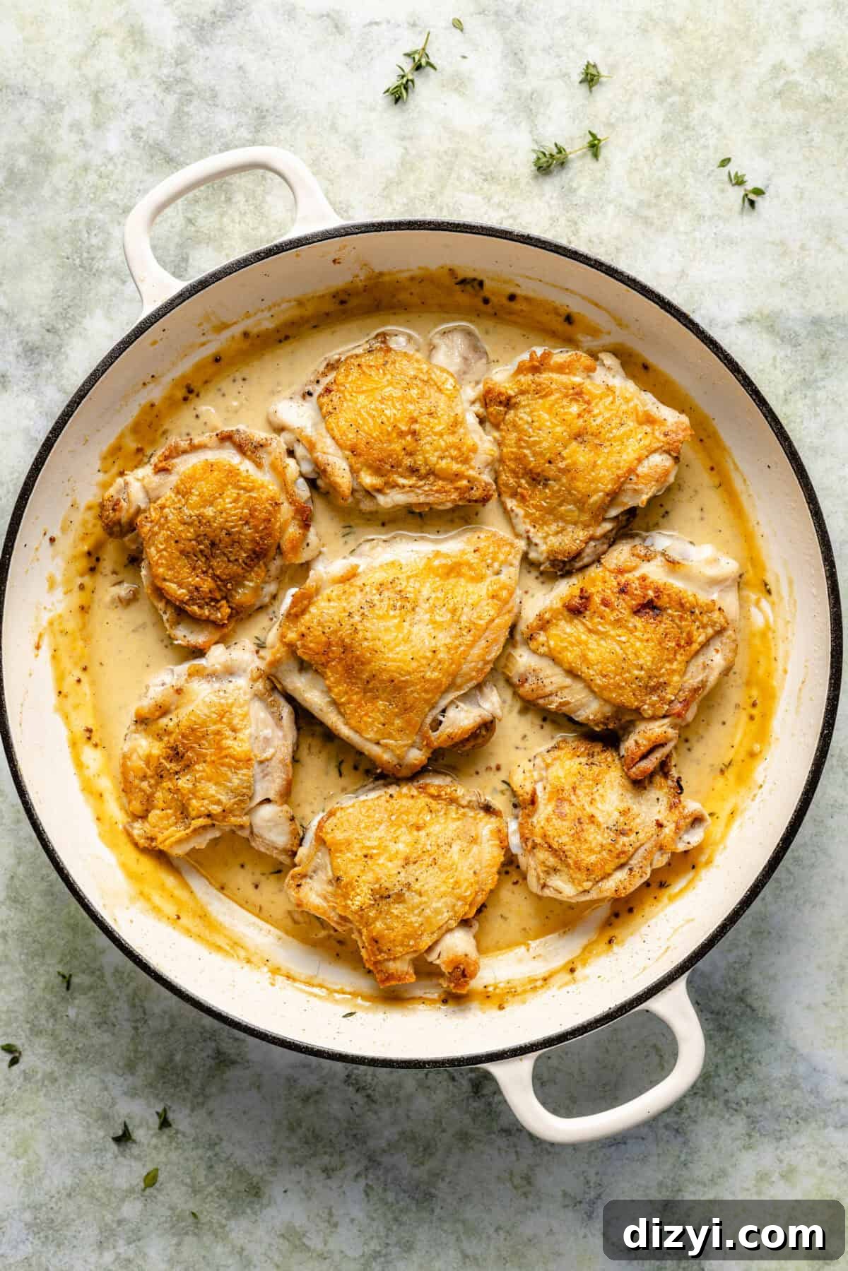Browned chicken in white cast iron skillet.