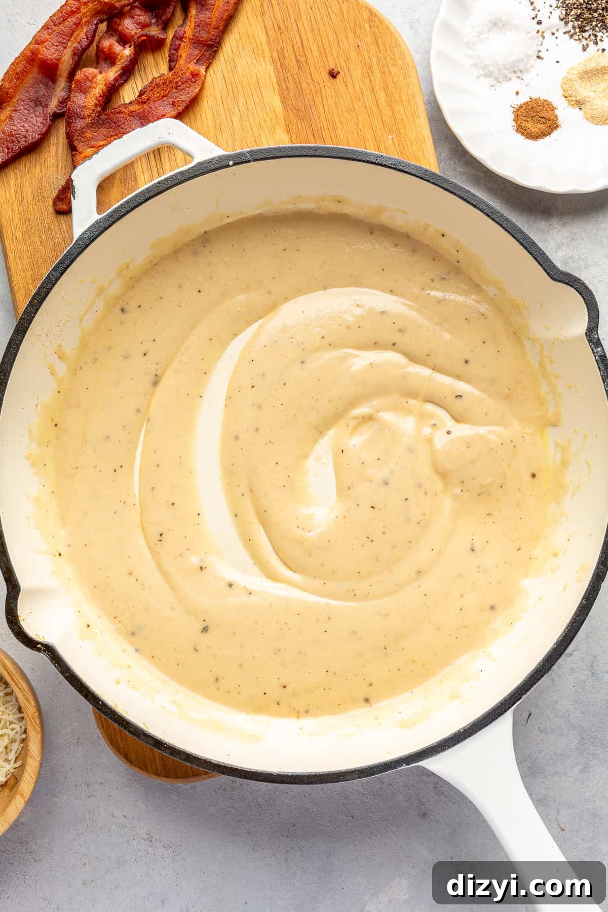 Cream sauce for Brussels Sprouts Au Gratin in white skillet.