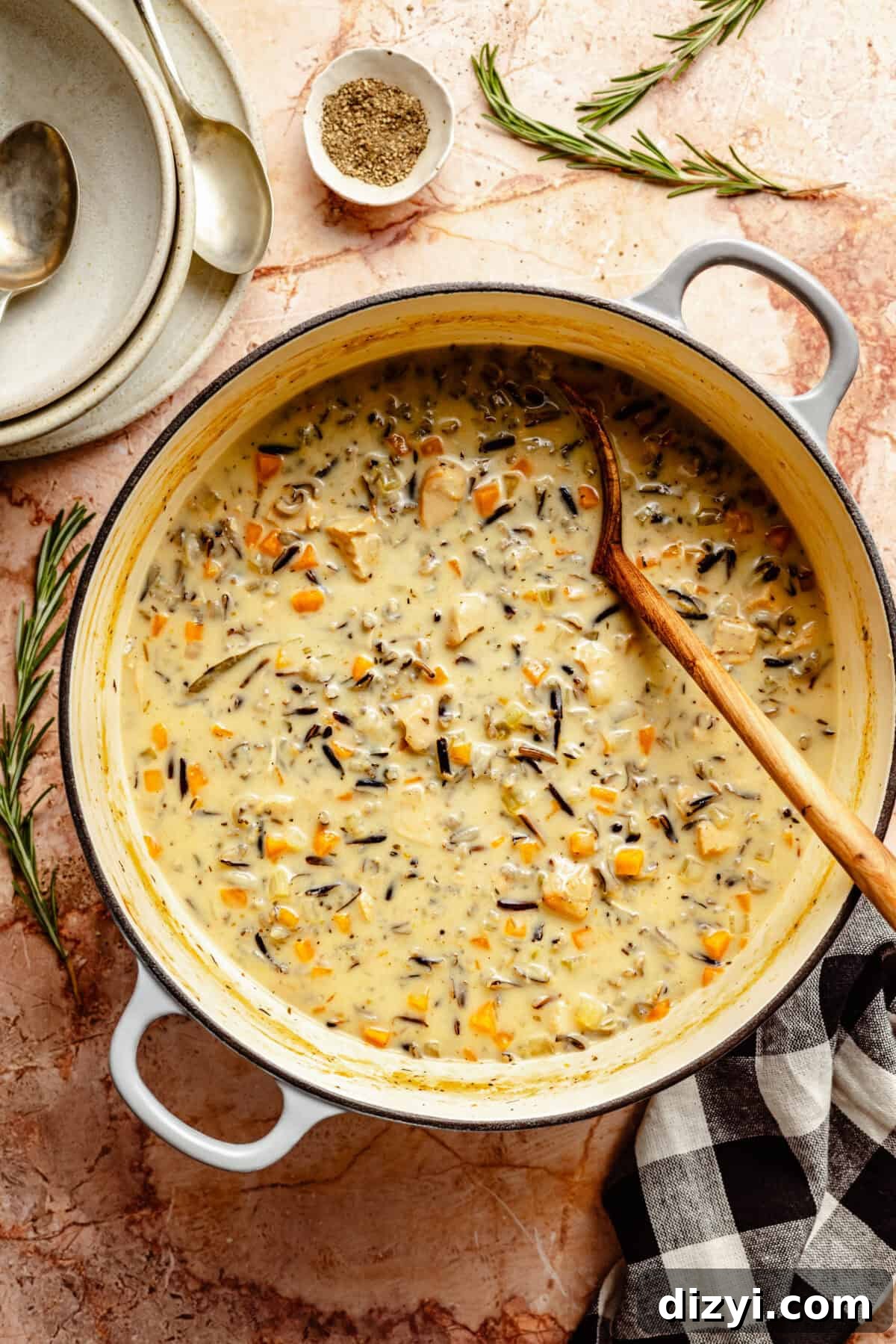 A finished pot of Dairy Free Chicken and Wild Rice Soup in a dutch oven with a wooden spoon.