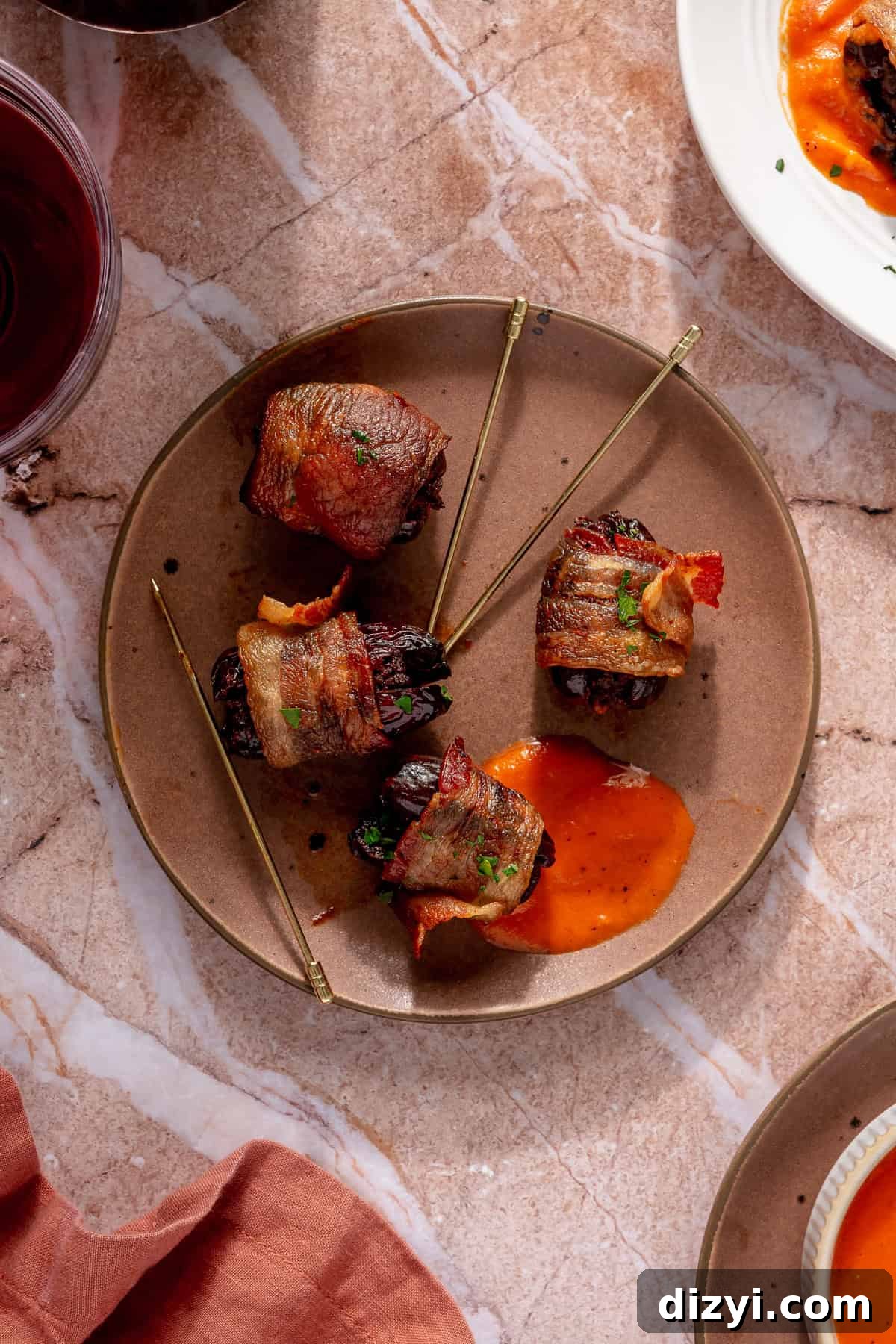 Crispy Bacon-Wrapped Dates Stuffed with Chorizo 2 A brown plate with four Chorizo-Stuffed Bacon-Wrapped Dates and a dab of sauce.