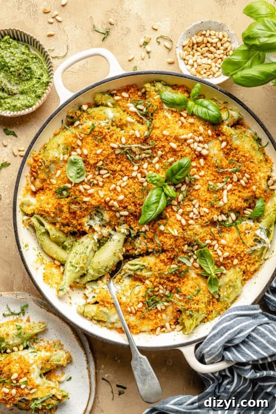 pesto unstuffed shells in braiser. spoon scooping pasta out.