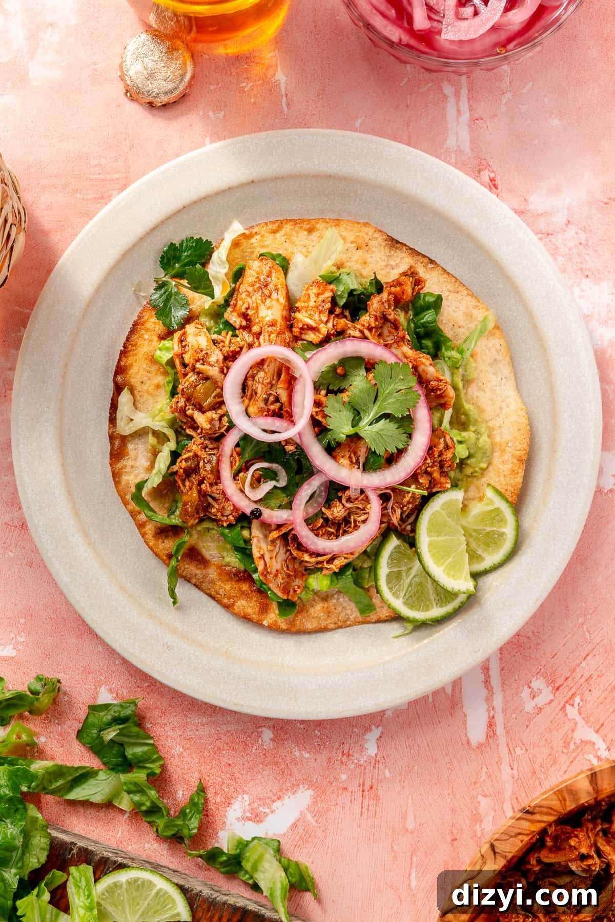 Leftover Turkey Recipes to Reinvent Dinner 11 Easy Rotisserie Chicken Tostadas with Quick Pickled Onions on a white plate with lime wedges.