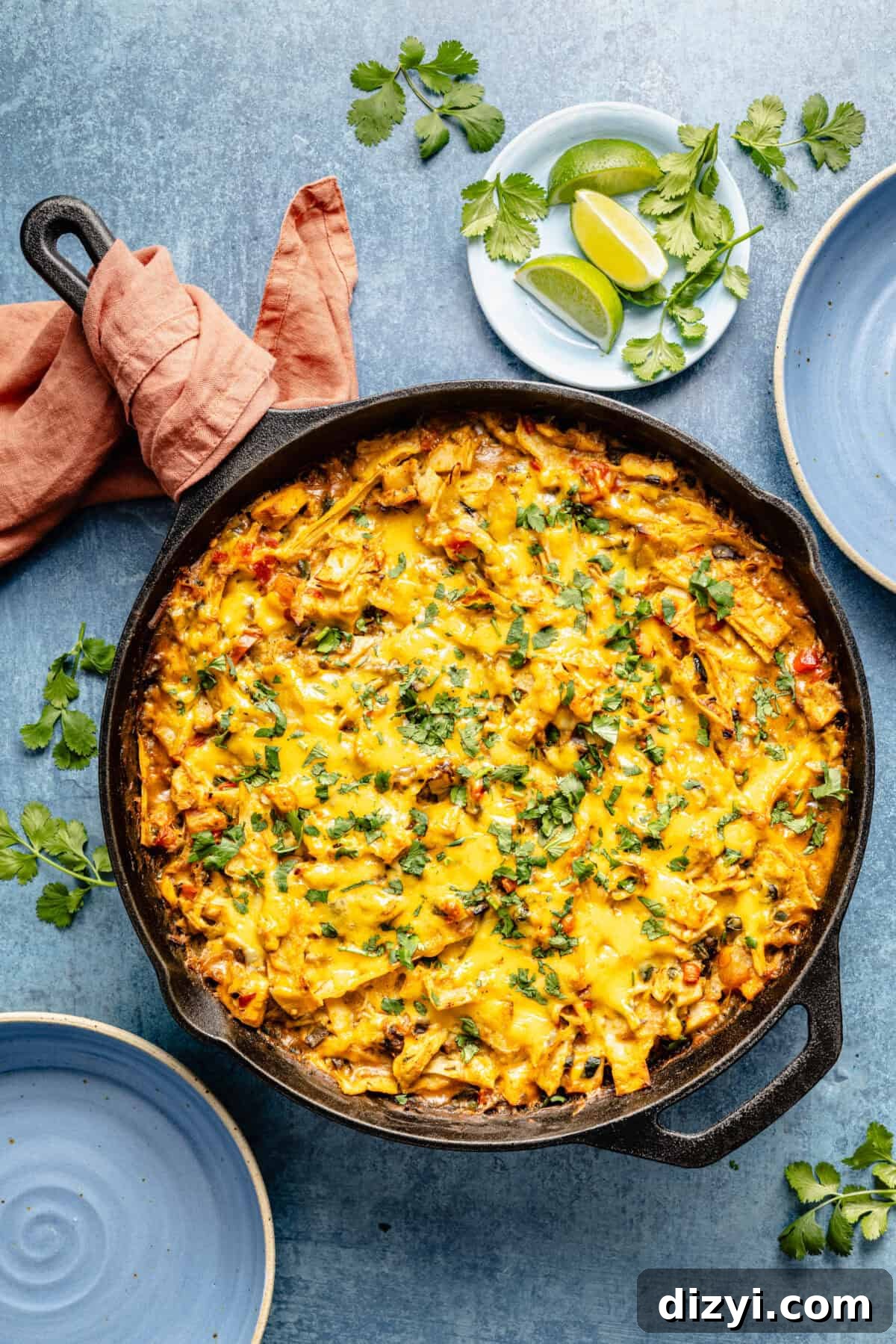 Leftover Turkey Recipes to Reinvent Dinner 15 cast-iron skillet with cheesy chicken casserole topped with chopped cilantro on a blue background