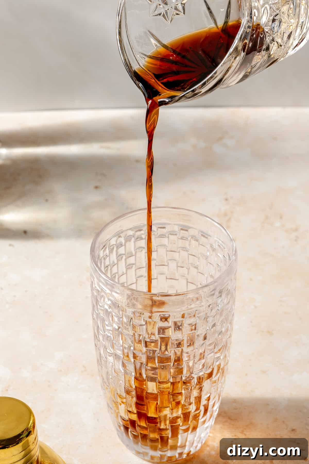 Kahlua pouring into glass cocktail shaker.
