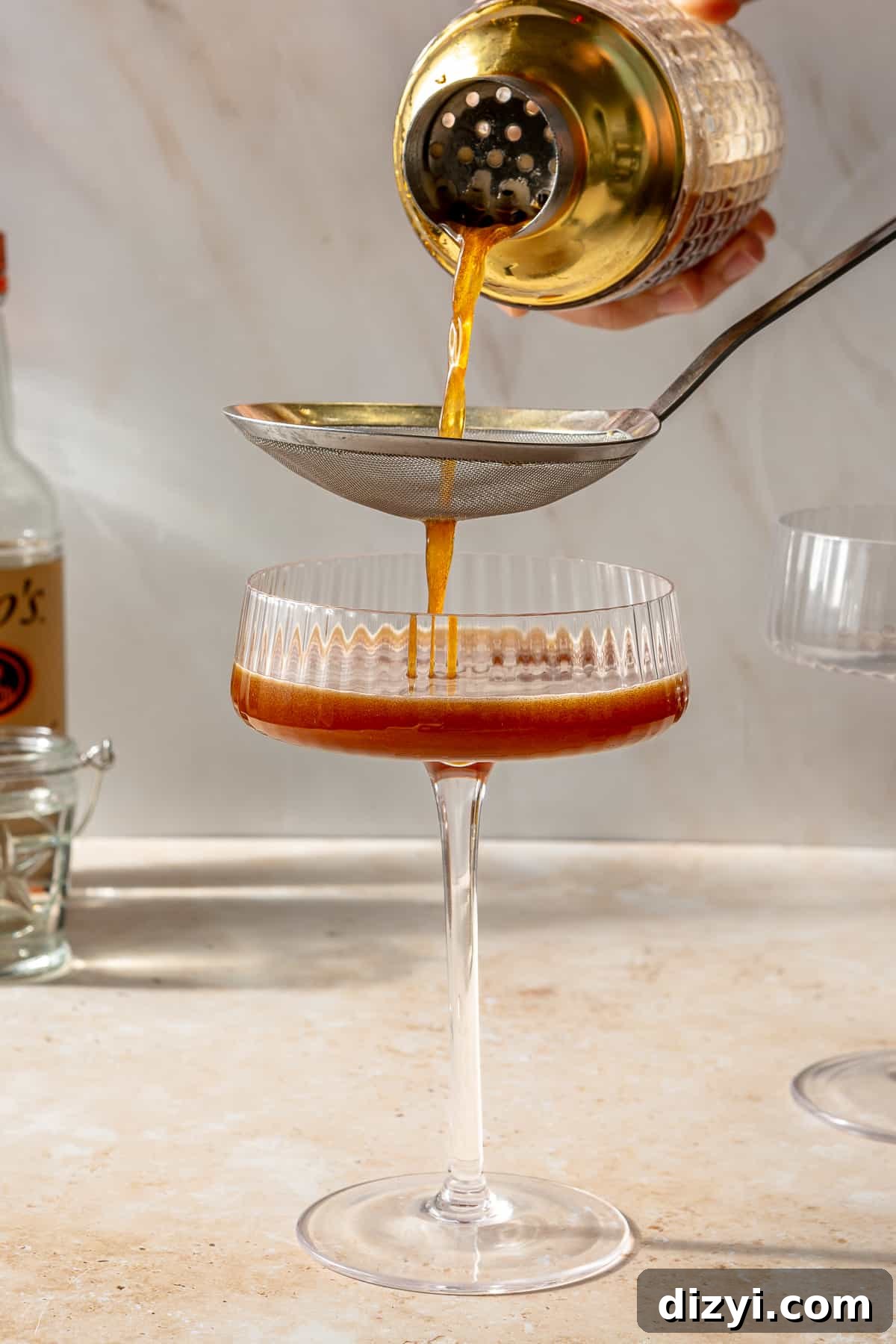 Espresso martini being strained into martini glass.