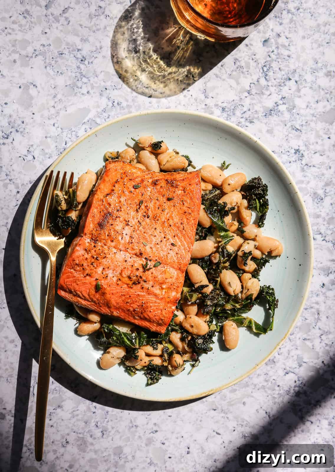 Broiled salmon on a bed of herby white beans and kale
