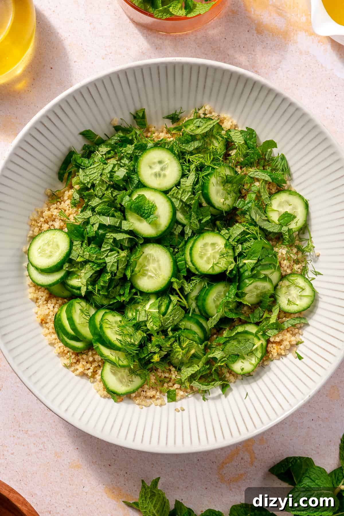 Cooked quinoa topped with herbs and cucumbers. Not combined.