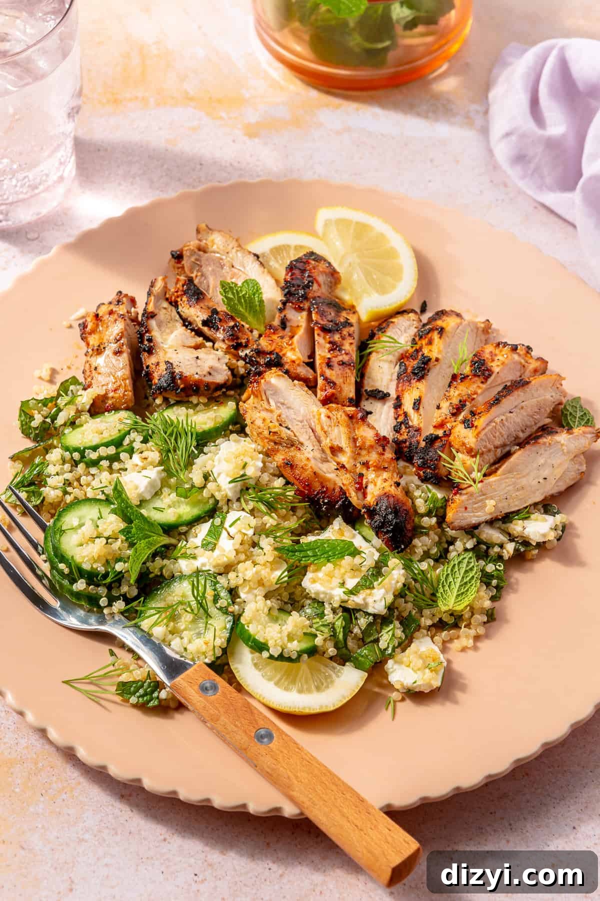 Harissa-Yogurt Marinated Chicken with Cucumber-Quinoa Salad in pink bowl with wooden fork.