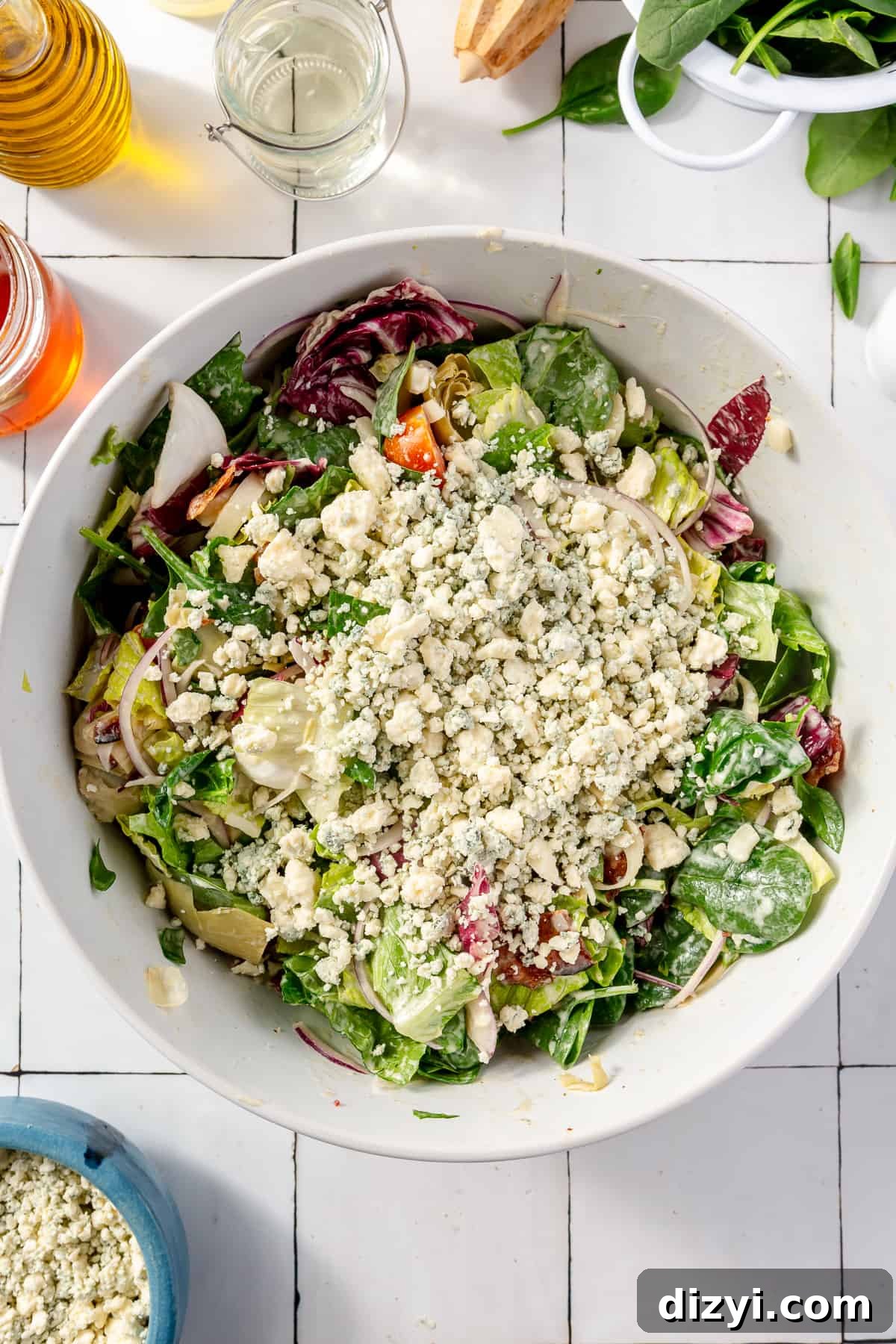 Tossed salad in large white bowl with gorgonzola on top.