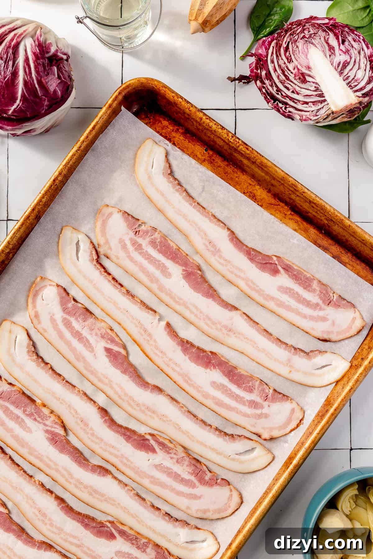 Raw bacon on a sheet pan lined with parchment paper. Other ingredients scattered around.