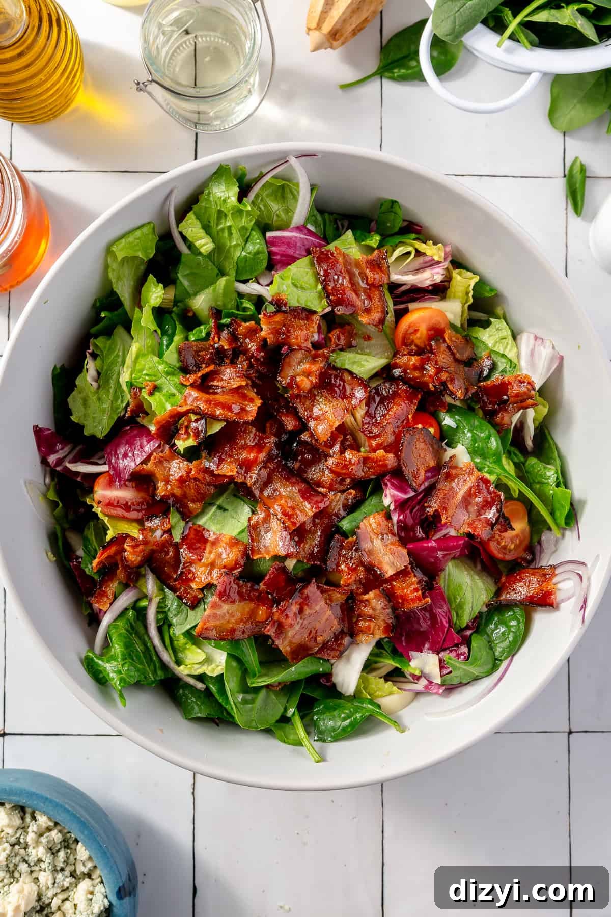 Tossed salad in large white bowl with chopped bacon on top.