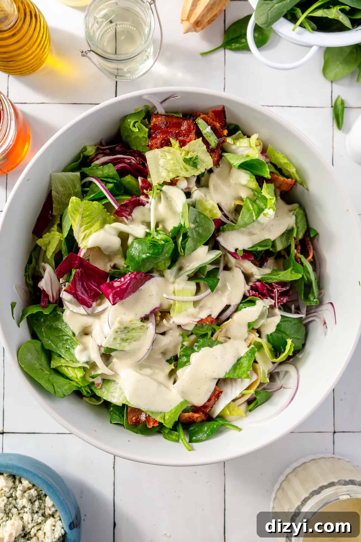 Tossed salad in large white bowl with dressing on top.