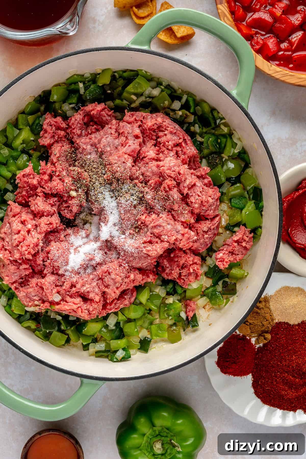 The veggies in the bottom of the pot with the ground beef added and spices on top.