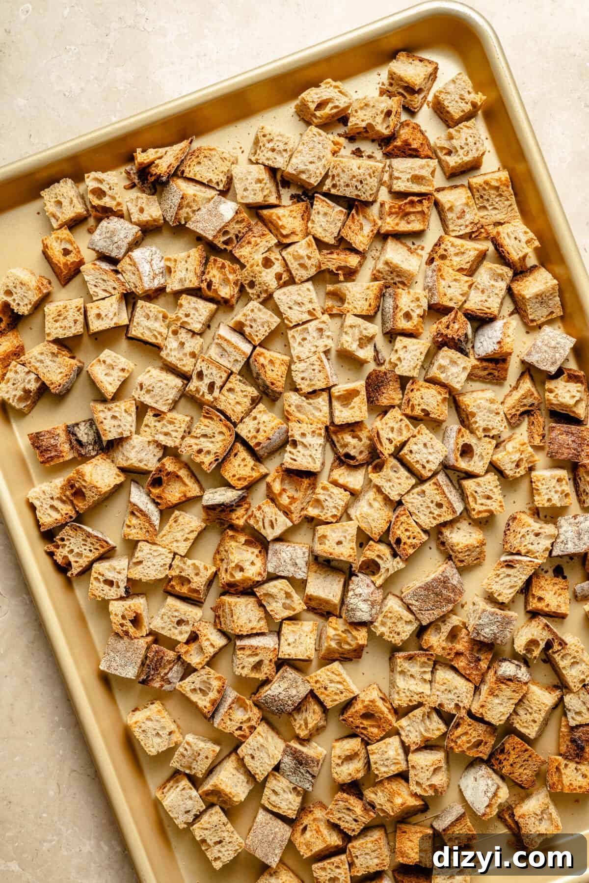 Oven-Baked Sausage and Sage Stuffing 3 a large sheet pan with toasted bread cubes on a neutral background