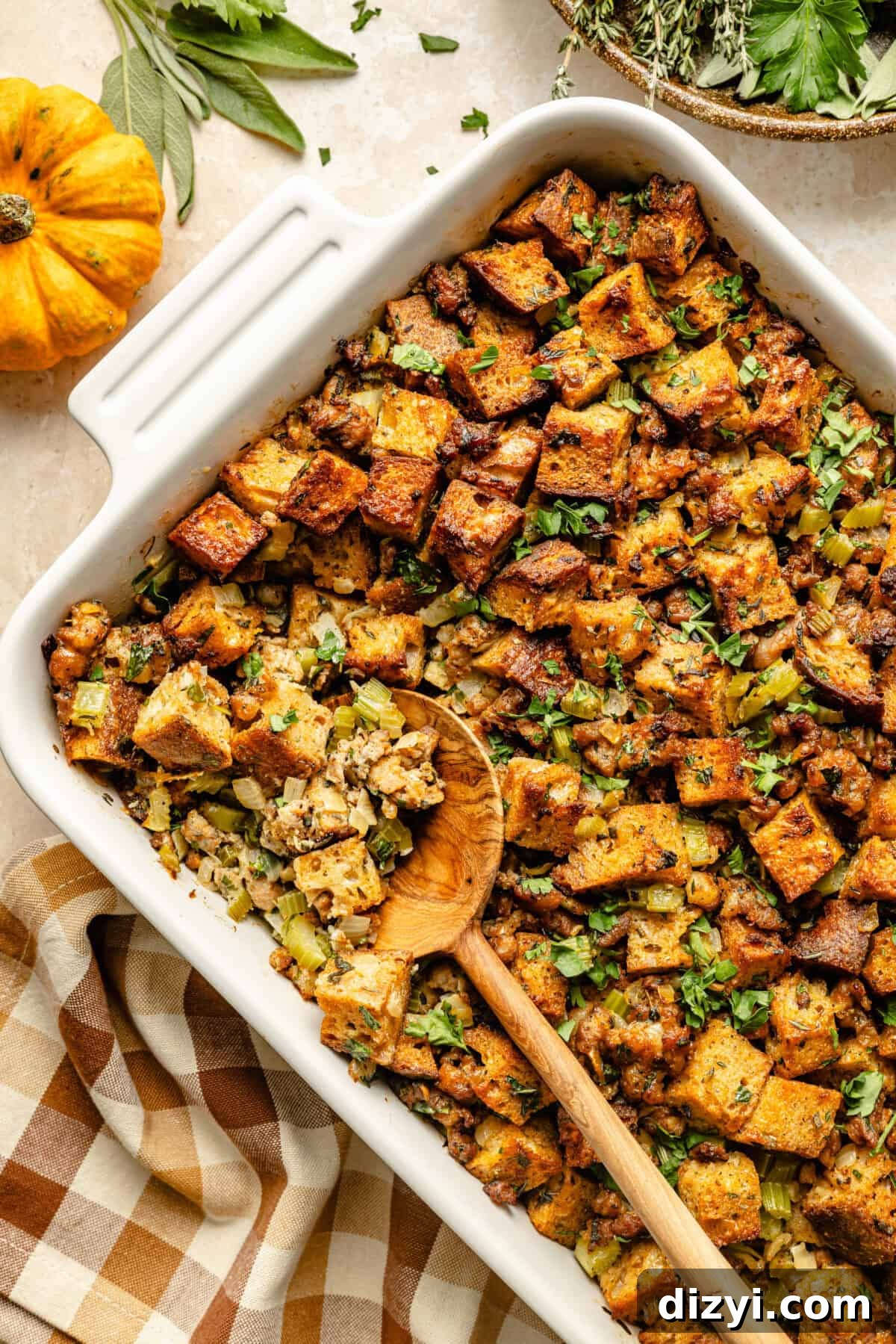 Oven-Baked Sausage and Sage Stuffing 6 a wooden spoon in a baking dish with baked stuffing for Thanksgiving