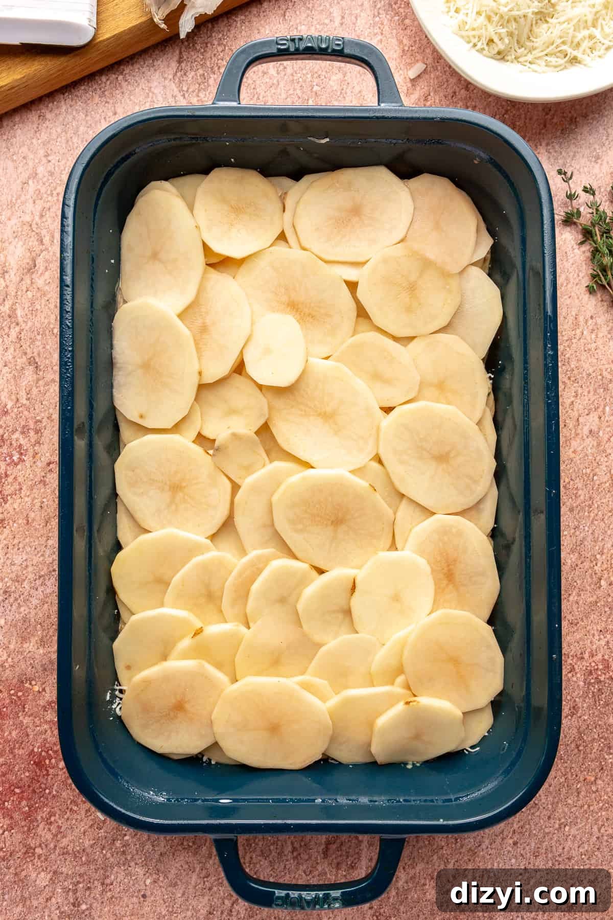 Creamy Scalloped Potatoes with Caramelized Onions 7 Uncooked Caramelized Onion Scalloped Potatoes in a blue baking dish.