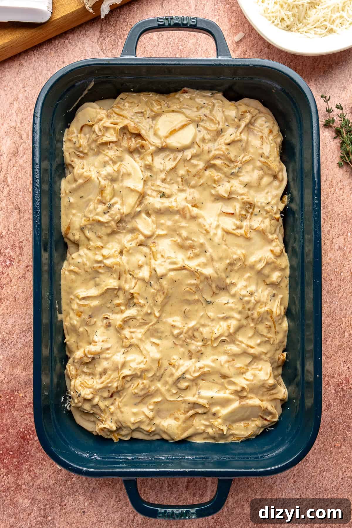 Creamy Scalloped Potatoes with Caramelized Onions 8 Uncooked Caramelized Onion Scalloped Potatoes in a blue baking dish.