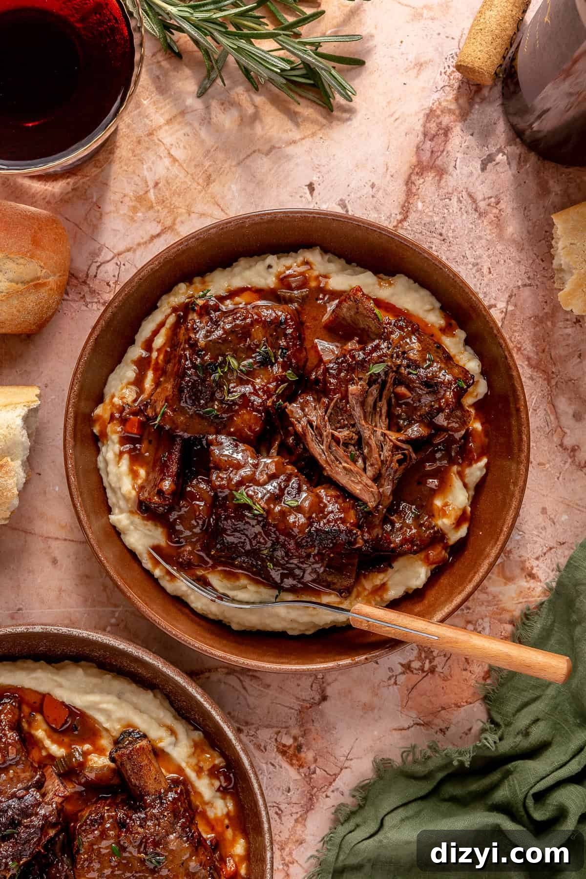 Braised Short Ribs in Red Wine with Parsnip-Potato Mash Recipe 2 A top-down look of a finished plate of Red Wine Braised Short Rib and Parsnip Potato Mash on a pink countertop with a fork.