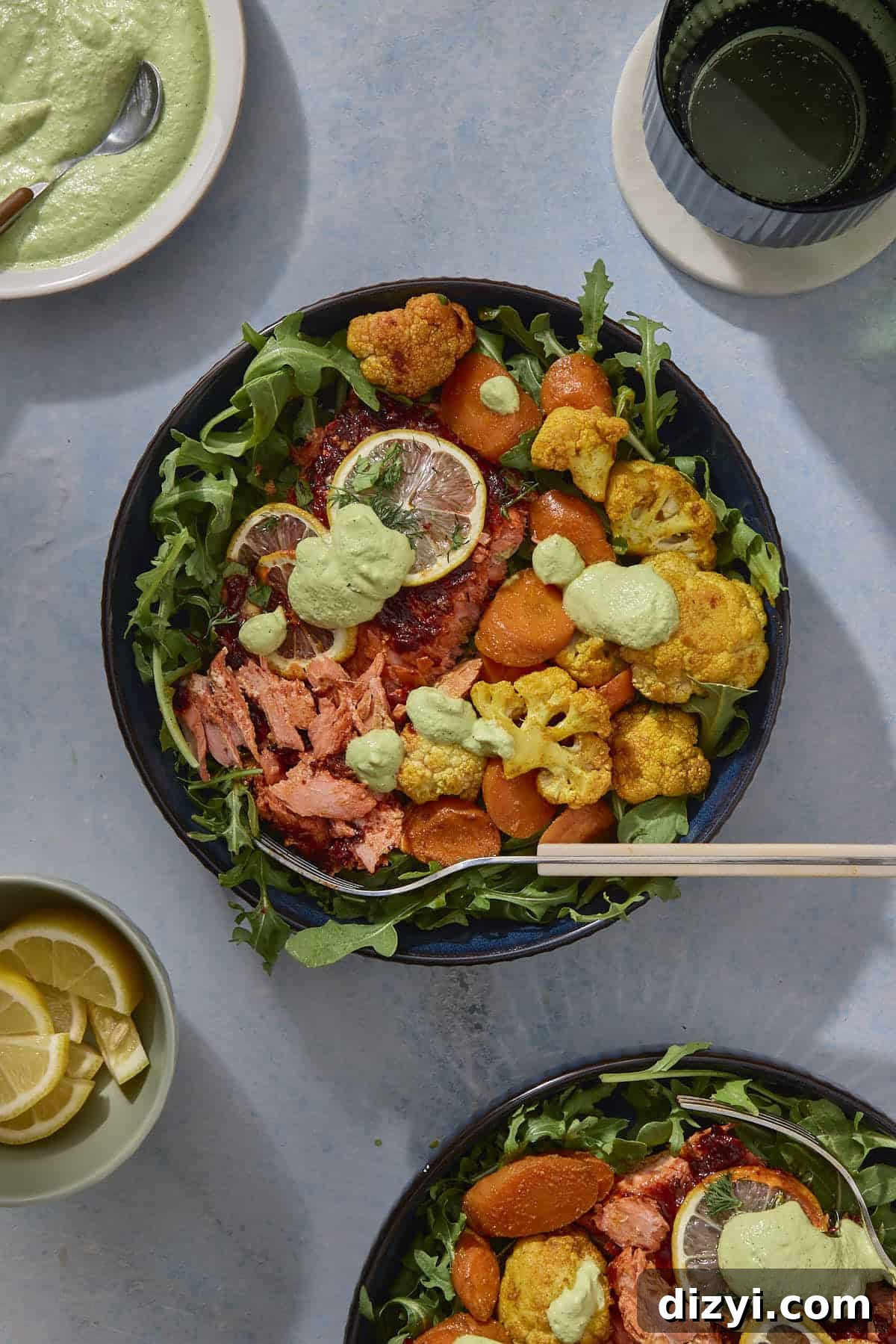 Sheet Pan Harissa Salmon + Roasted Veggies with Cashew Crema served in bowl with arugula.
