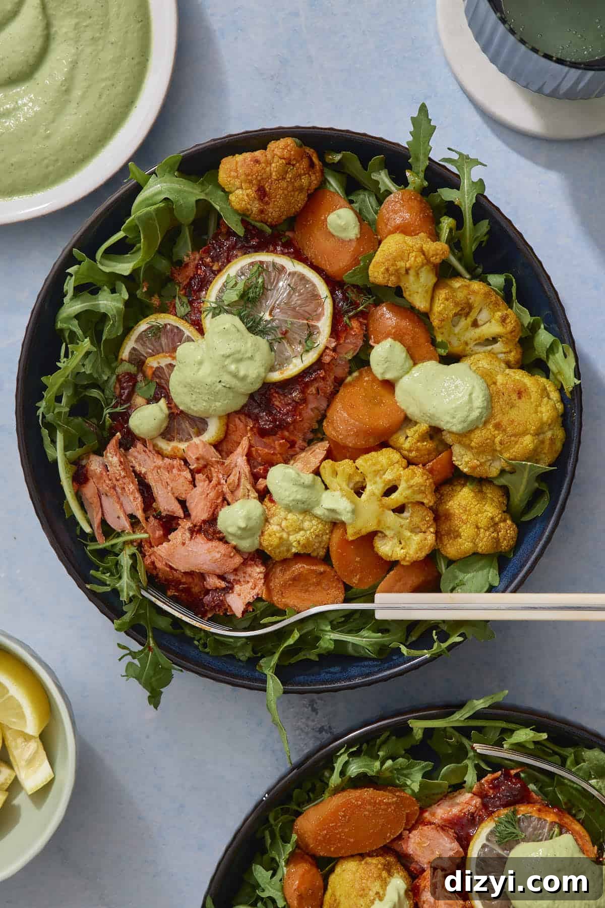 Sheet Pan Harissa Salmon + Roasted Veggies with Cashew Crema served in bowl with arugula.