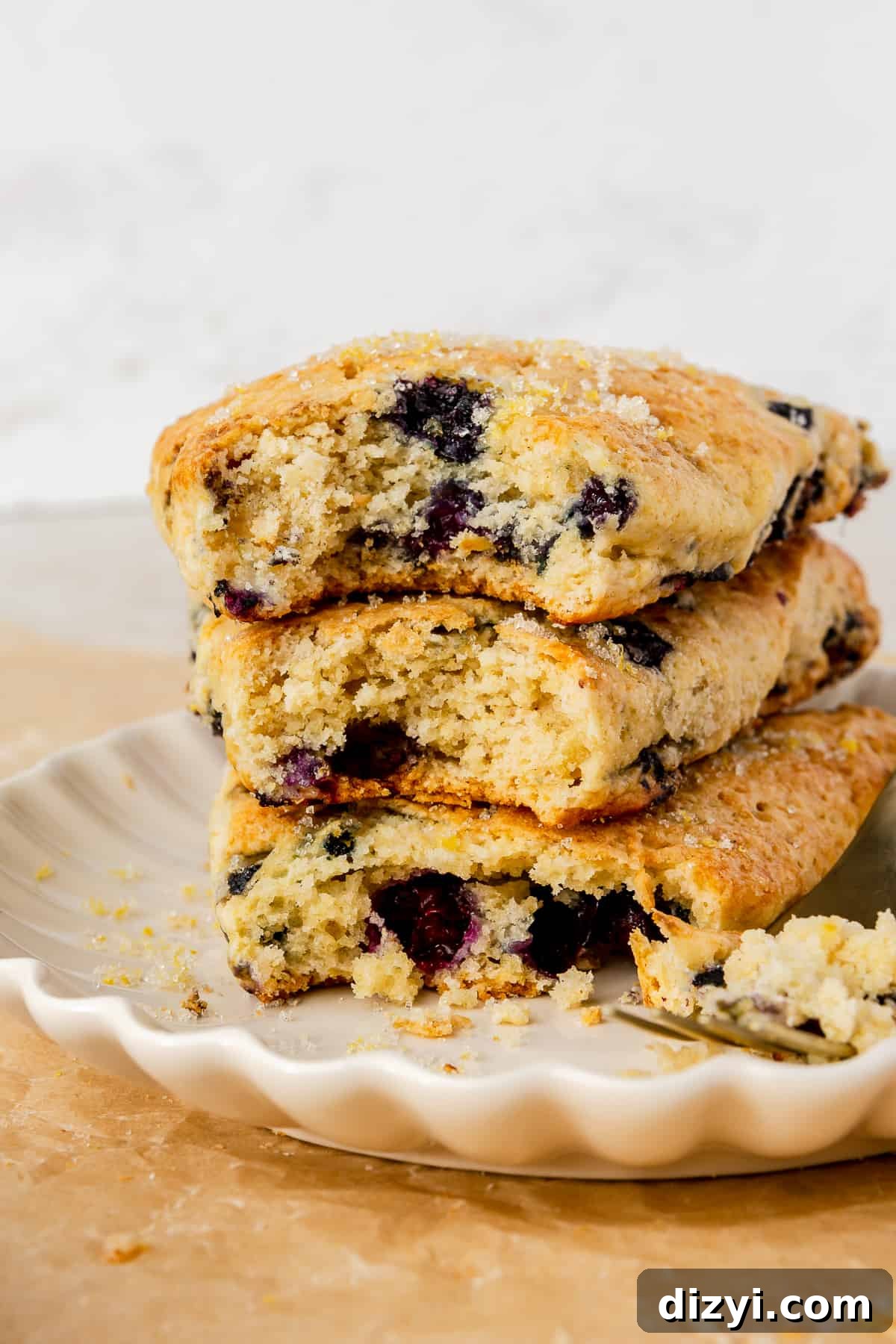 Three scones stacked on top of each other on white plate. Bites taken out of scones.