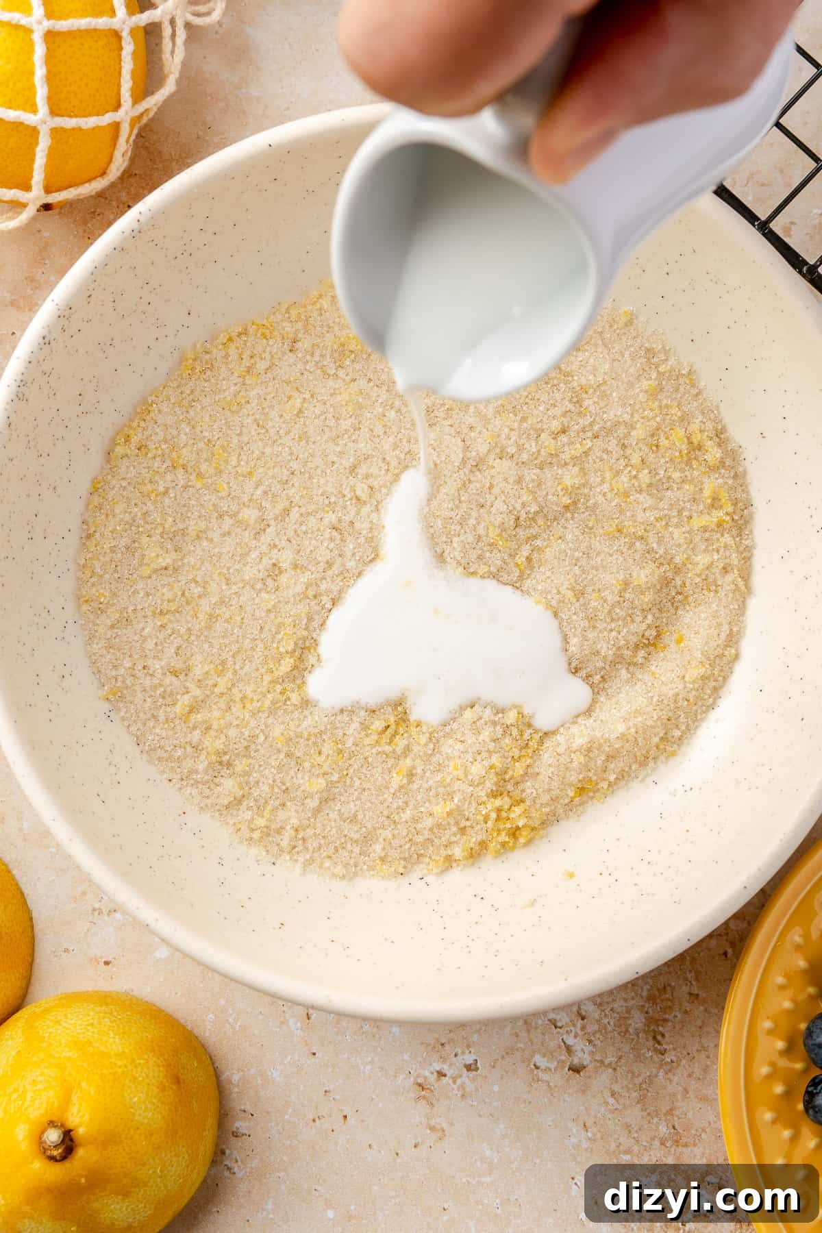 Buttermilk pouring into bowl of lemon zest and sugar mixture. 