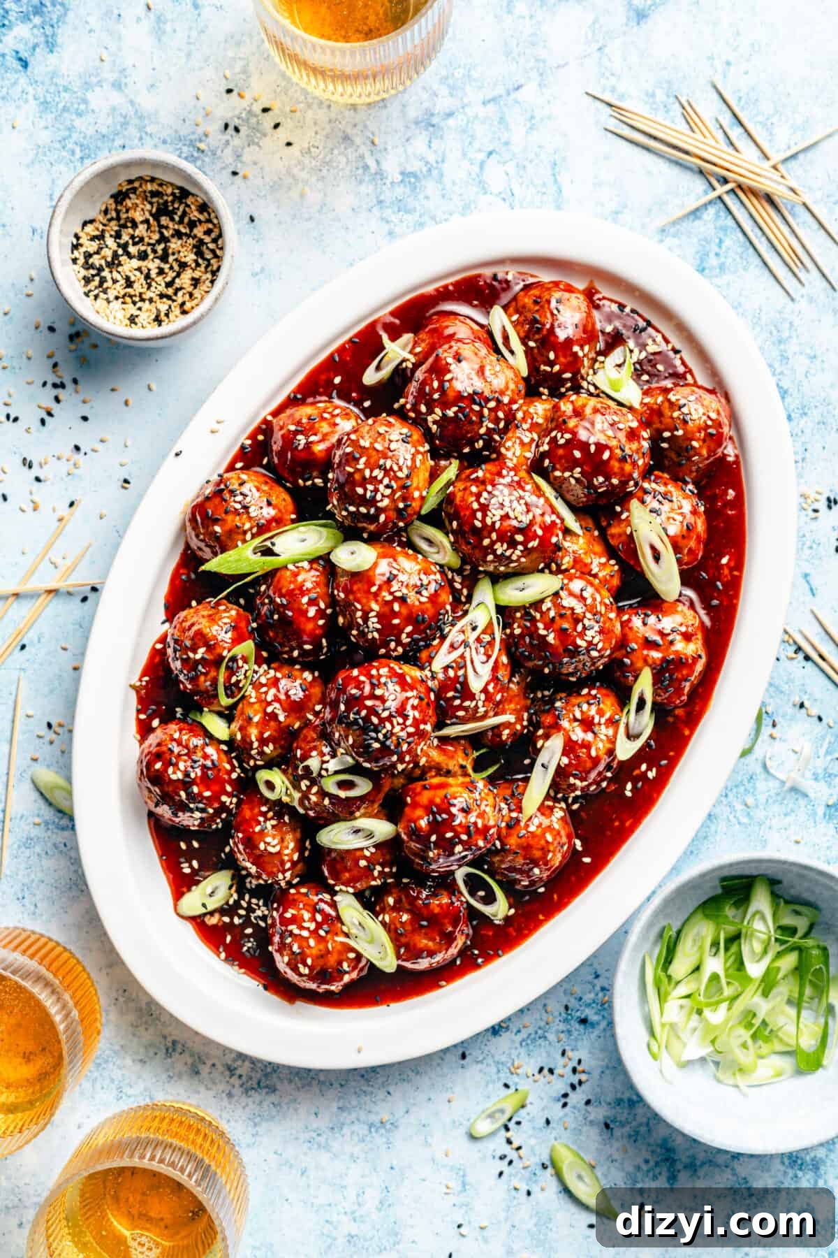 Korean-Inspired BBQ Chicken Meatballs on white oval platter with beer in corner plus other garnishes.