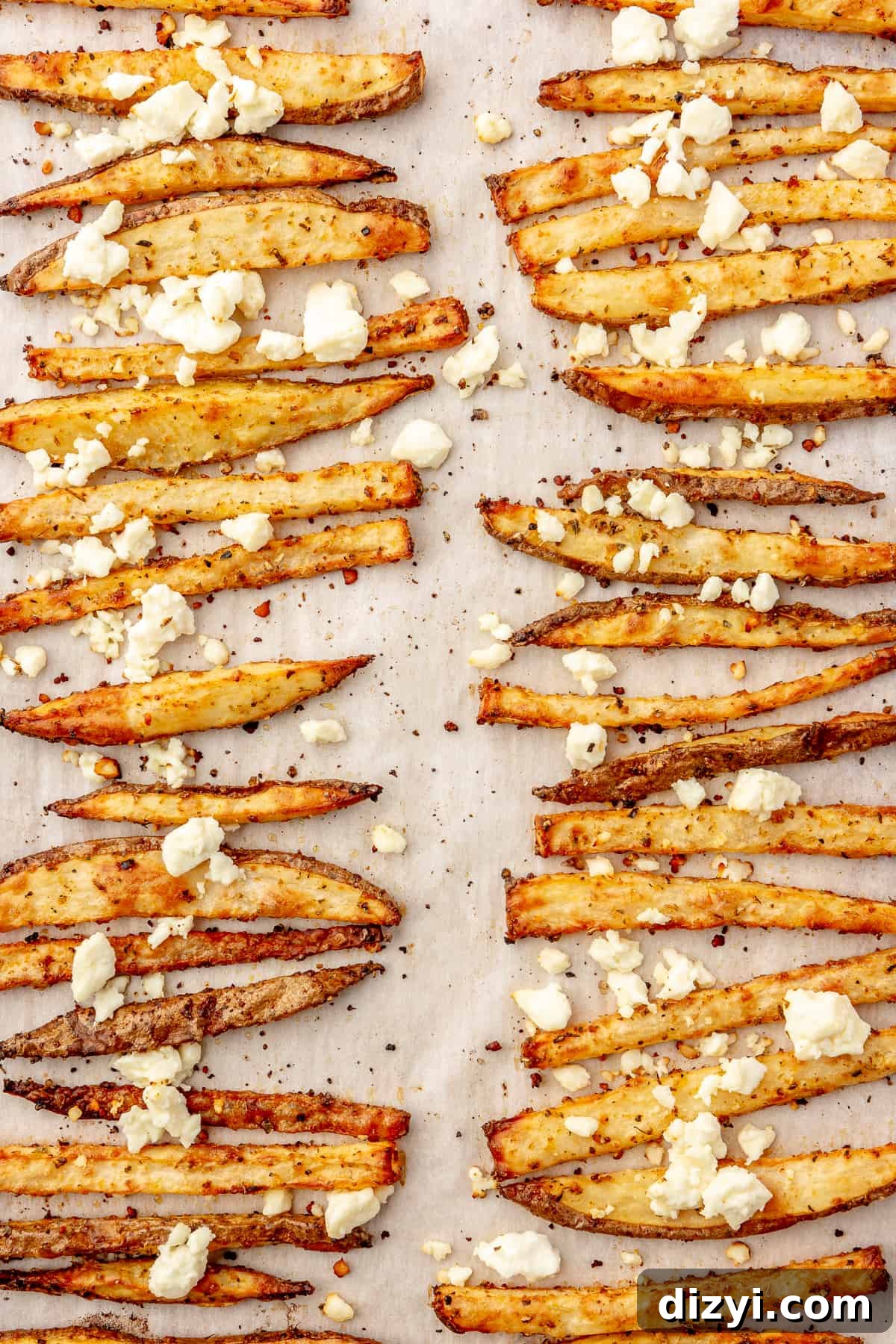 Crispy Greek Feta Fries with Romesco Ranch Dip 6 Baked fries in two rows topped with crumbled feta on a sheet pan.
