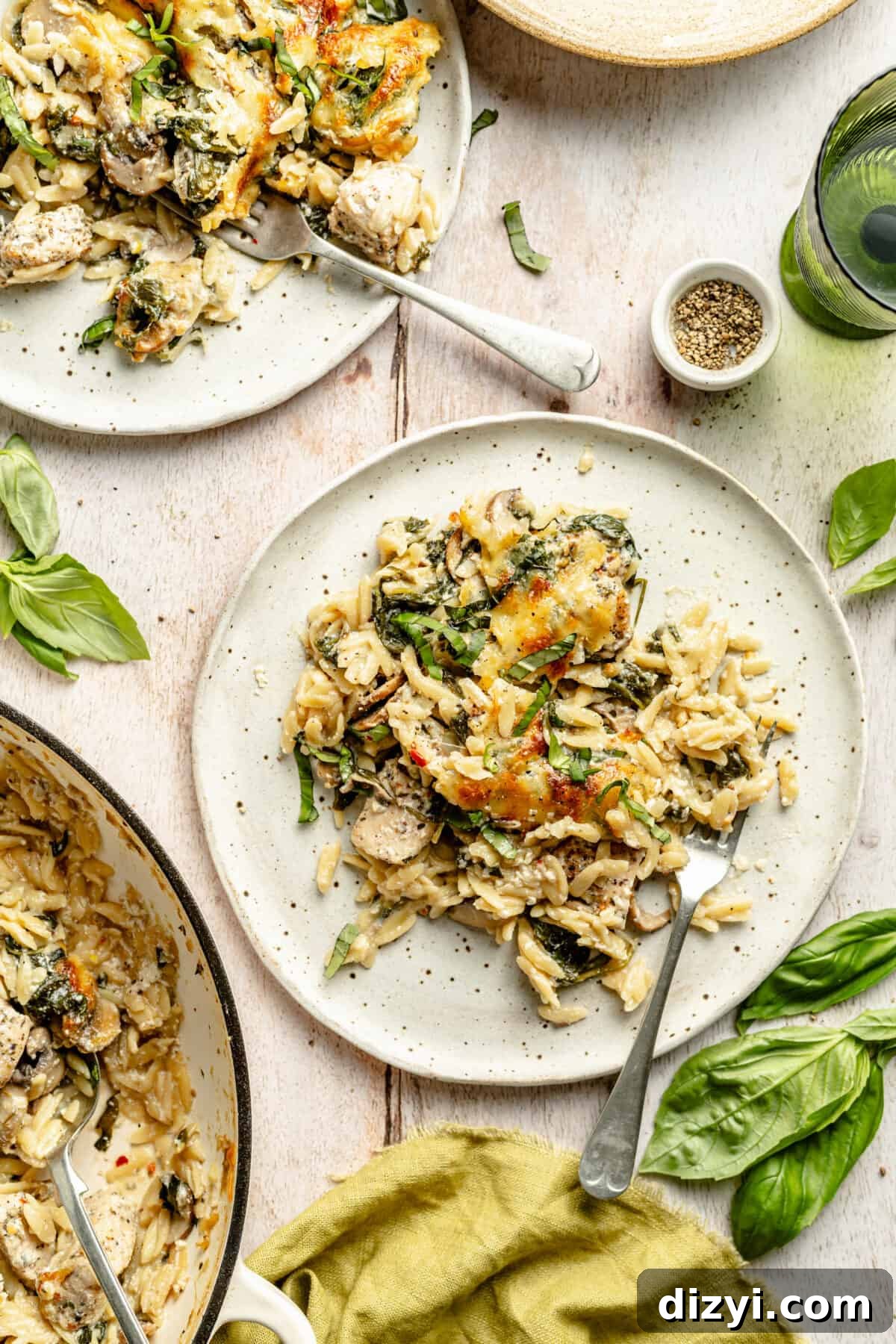Creamy Ricotta Chicken and Orzo Skillet plated on two plates with skillet peeking in.