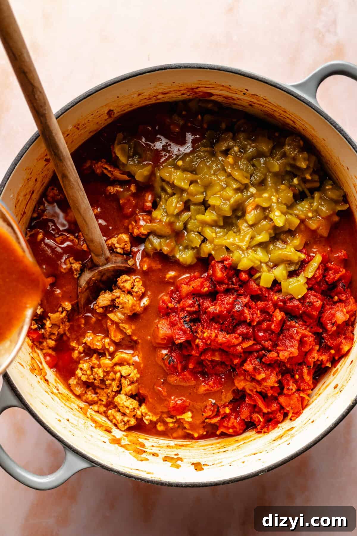 Cheesy Chicken Enchilada Chili Recipe 5 Large pot of ground chicken with tomatoes and green chiles in it. Enchilada sauce being poured into pot.