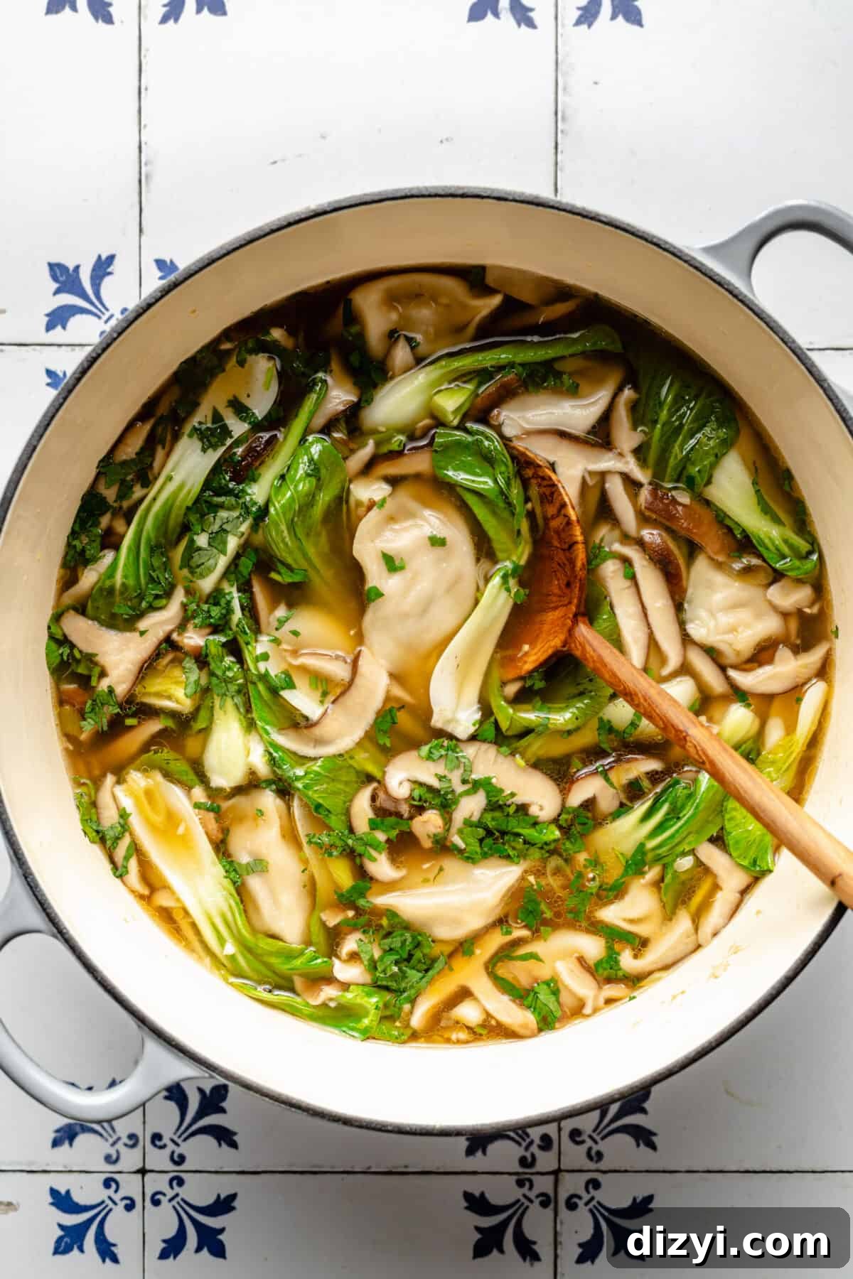 White dutch oven pot of 20-Minute Wonton Soup. Spoon resting inside.