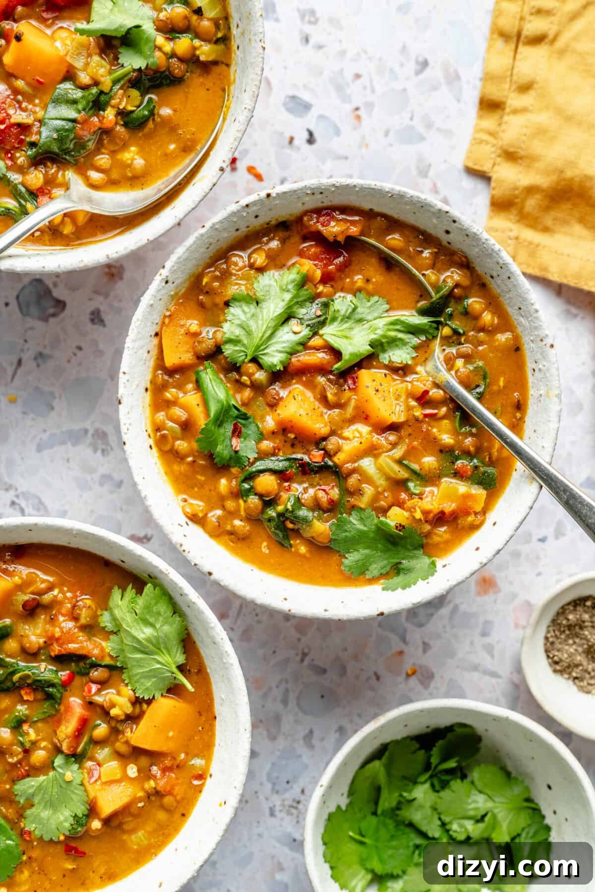 Three small white bowls of Curried Lentil Soup. All garnished with cilantro.