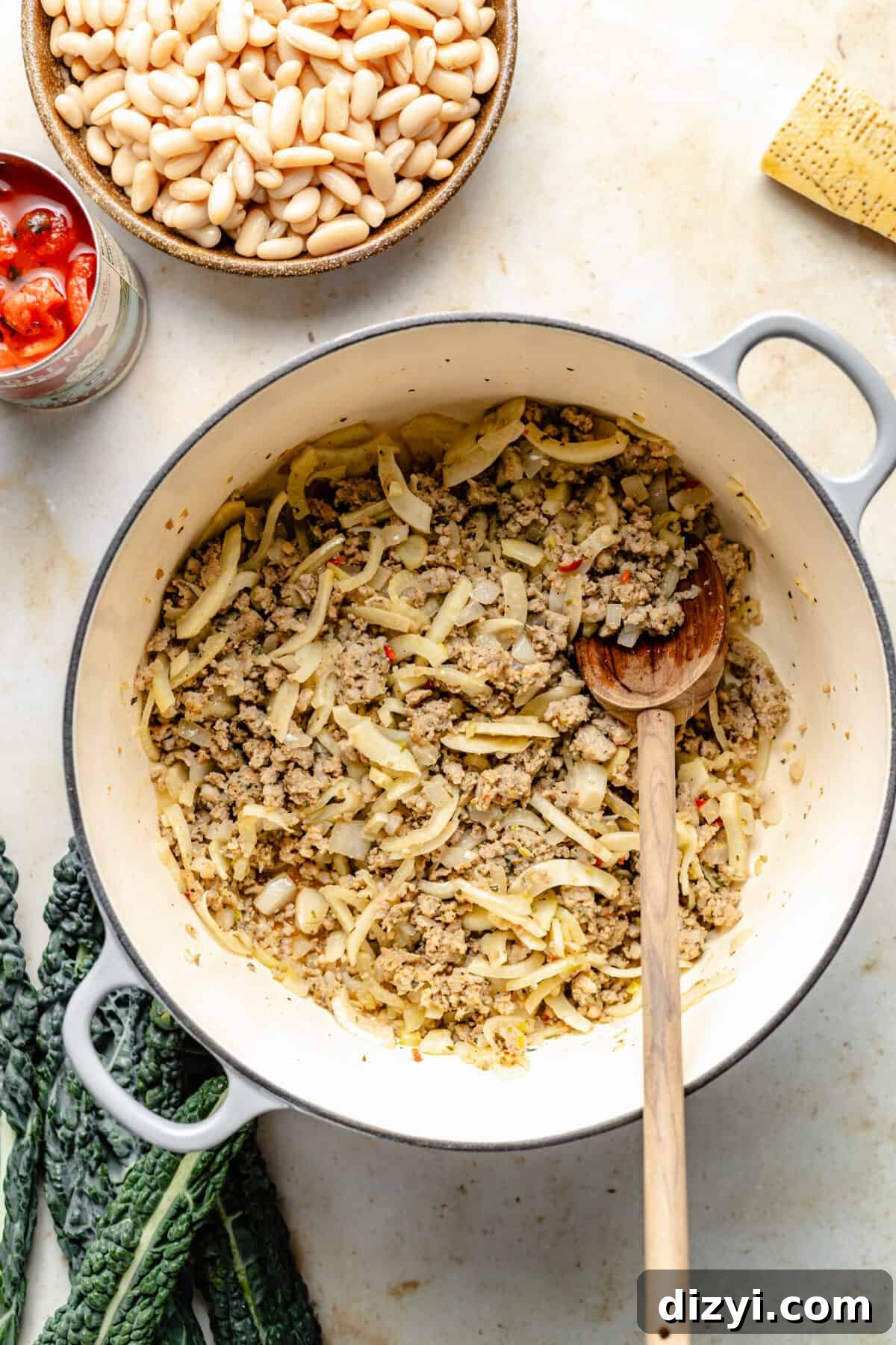 White dutch oven with ground beef and fennel sautéing.