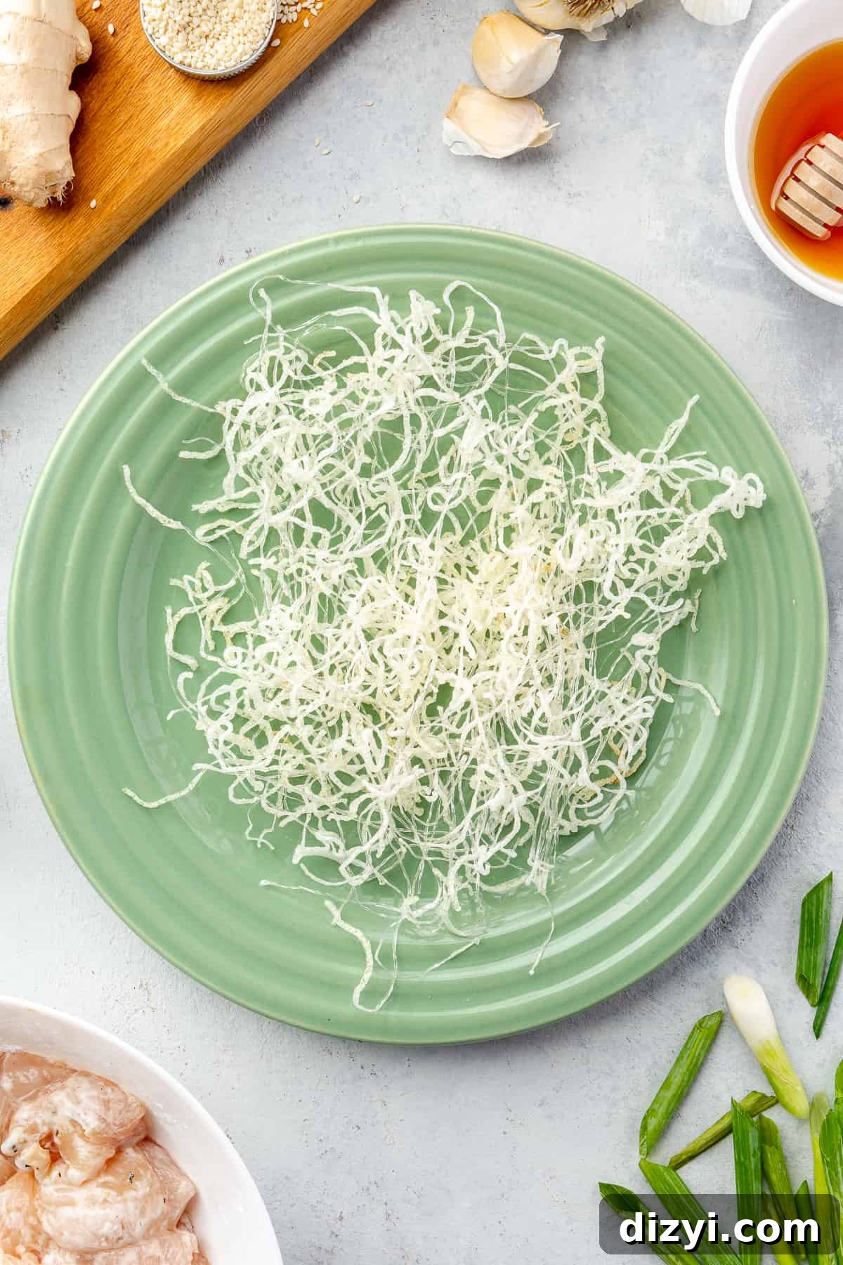 How to Make Honey Garlic Chicken Lettuce Wraps 5 Crisp mung bean noodles on a green plate with other ingredients scattered around it.