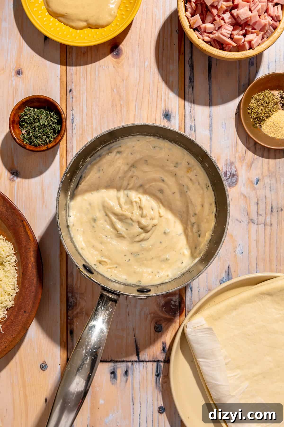 Bechemal for Mini Croque Monsieur Bites in a small saucepan. Other ingredients scatter around.