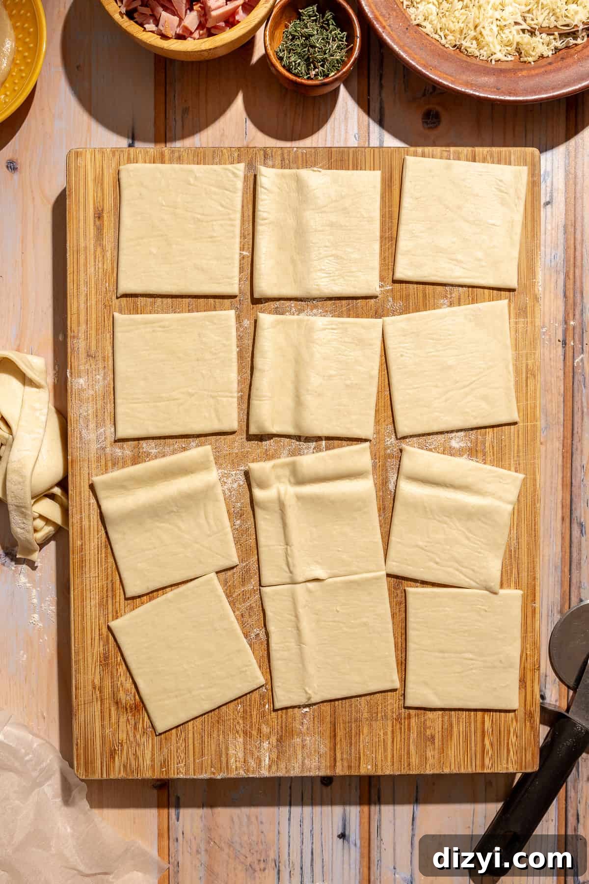 Cut puff pastry on wooden cutting board for Mini Croque Monsieur Bites.