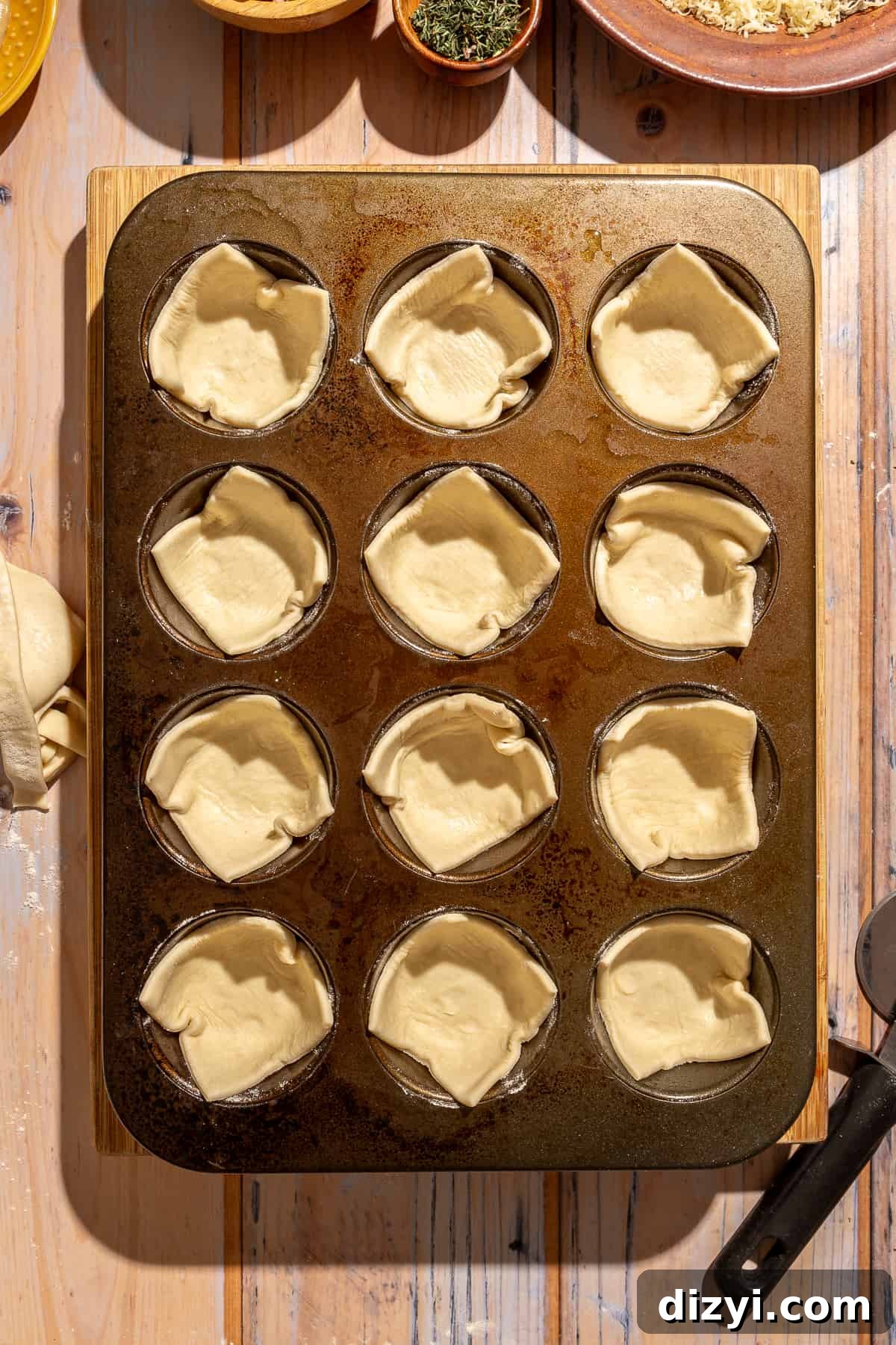 Cut pastry placed into each muffin pan opening.