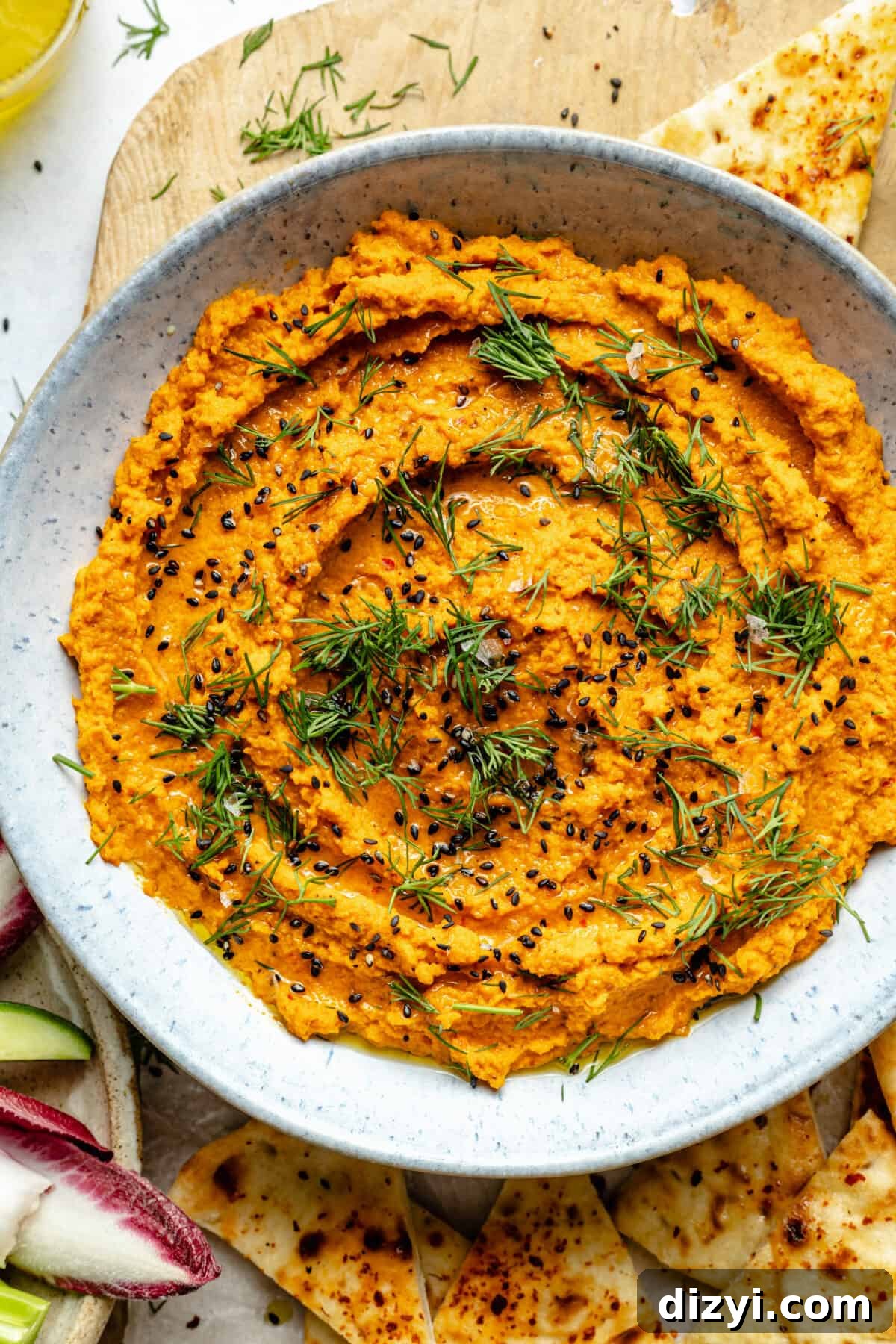 Close up of Harissa Carrot Dip in bowl. Dill and black sesame seeds on top.