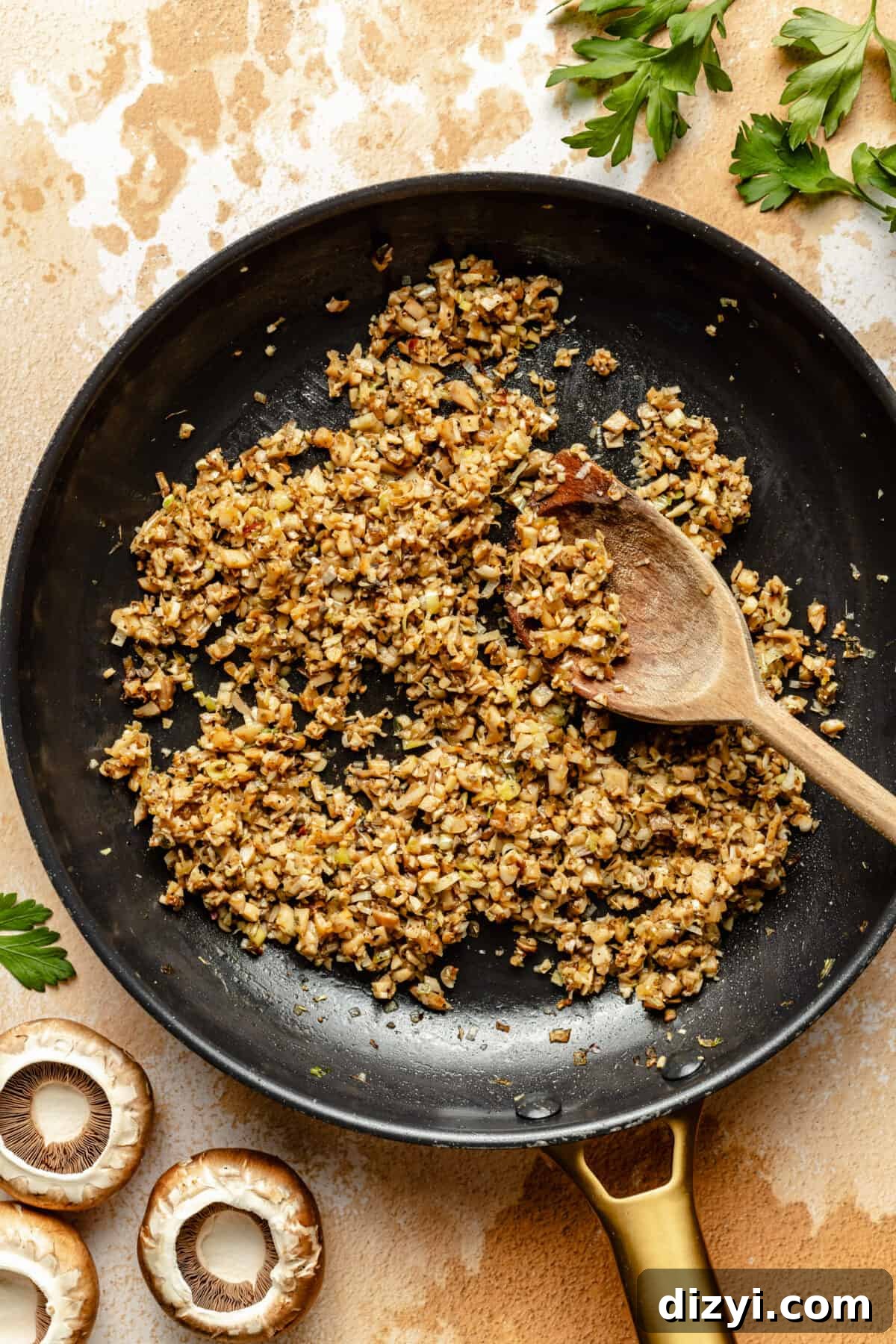 Sausage Stuffed Mushrooms with Garlic and Parmesan 4 Sausage and chopped mushrooms in black saute pan. Wooden spoon laying in pan.