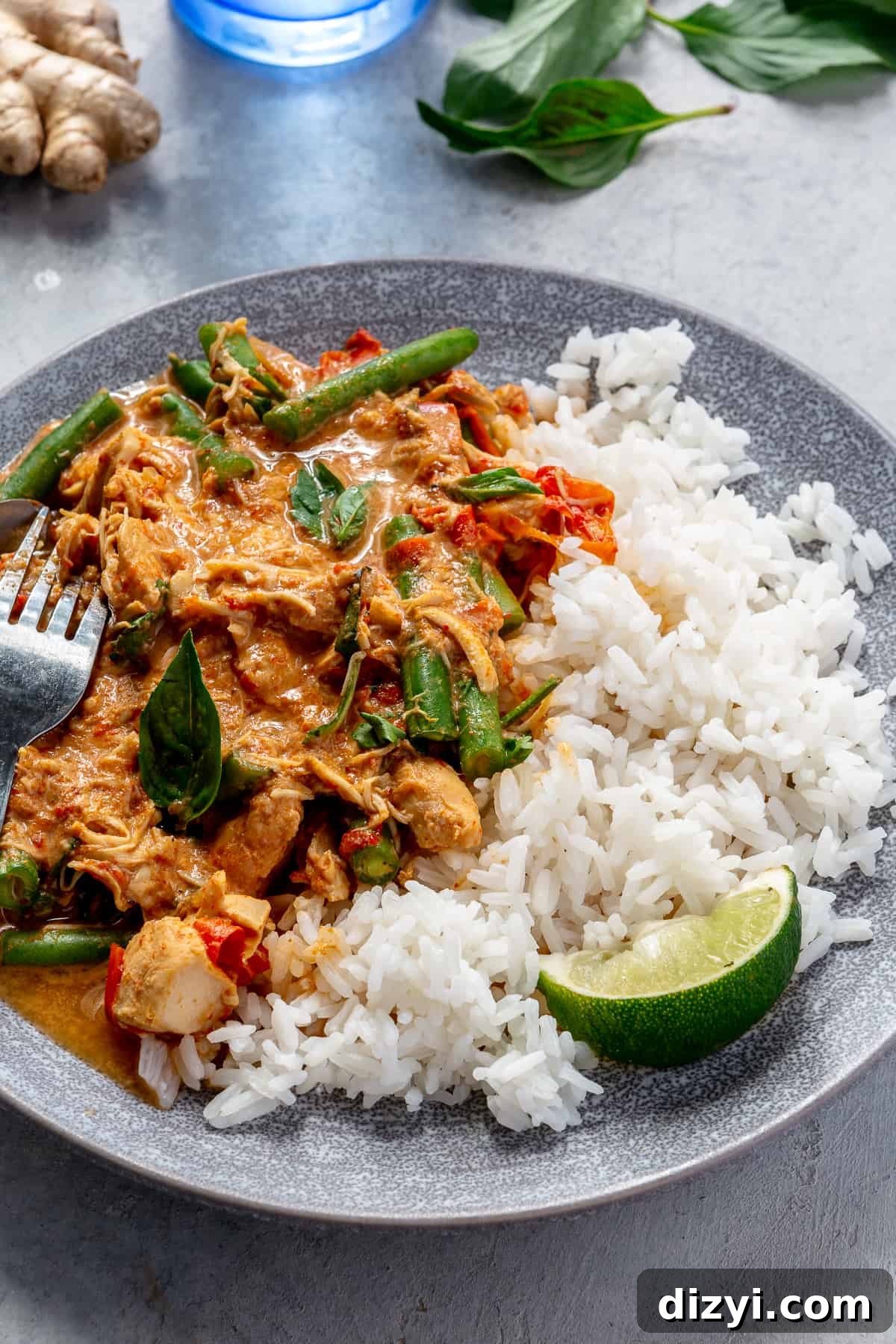 Slow Cooker Thai Red Curry with Chicken and Vegetables 8 Angle view of blue bowl filled with Slow Cooker Thai Red Curry Chicken and Veggies and rice.