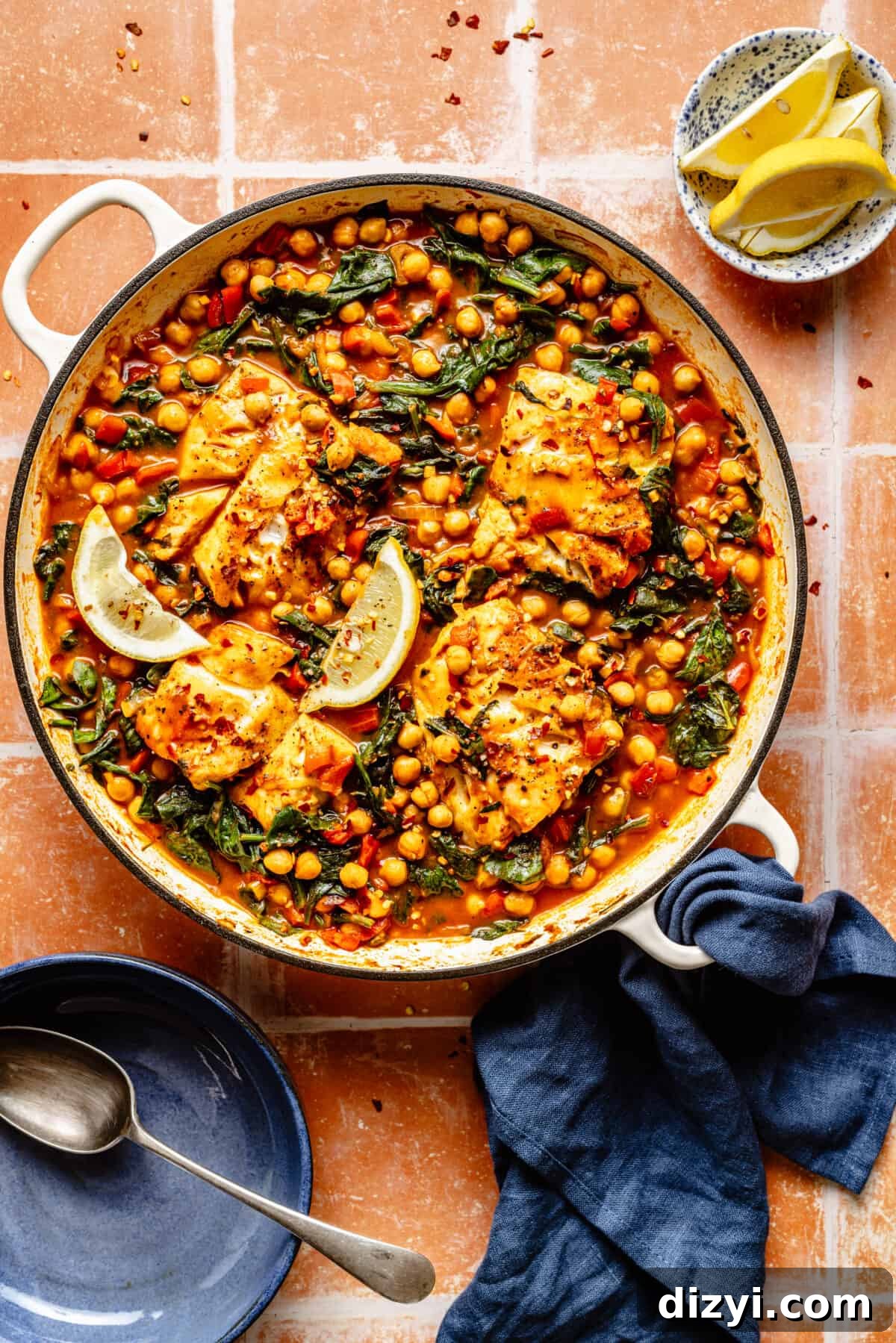 Spanish-Inspired Simmered White Fish in white skillet on tiled counter.